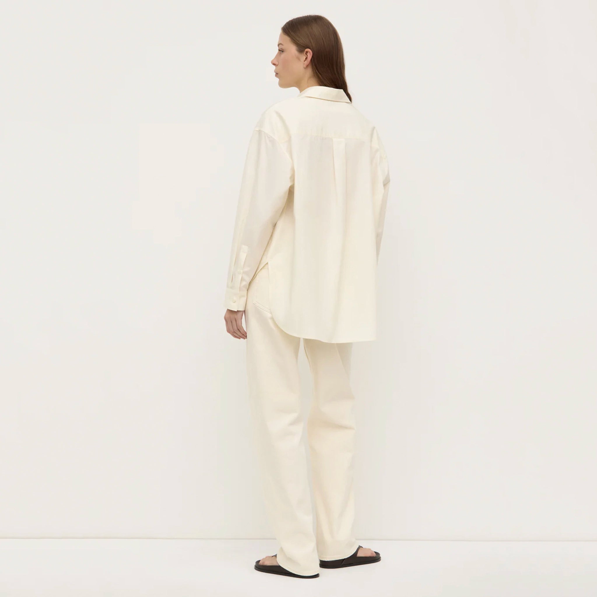 Person wearing a white suit standing against a plain background