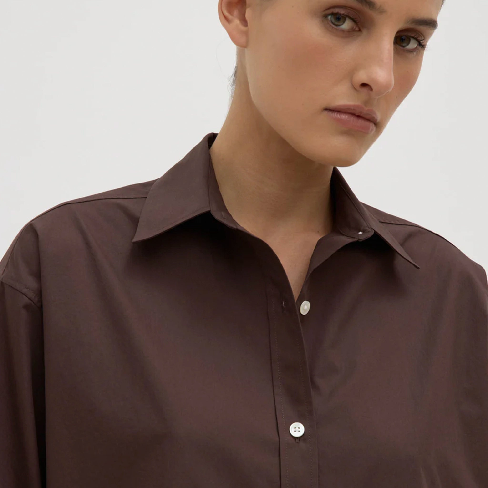 Woman wearing a brown shirt against a plain background