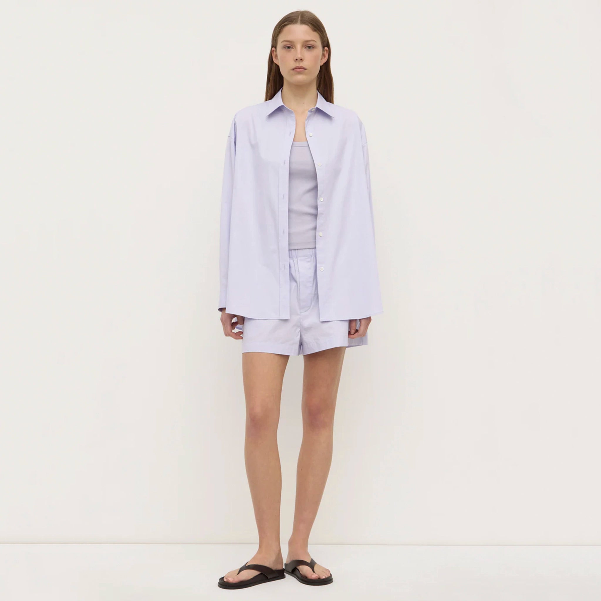 Woman wearing a light purple shirt and shorts set on a white background