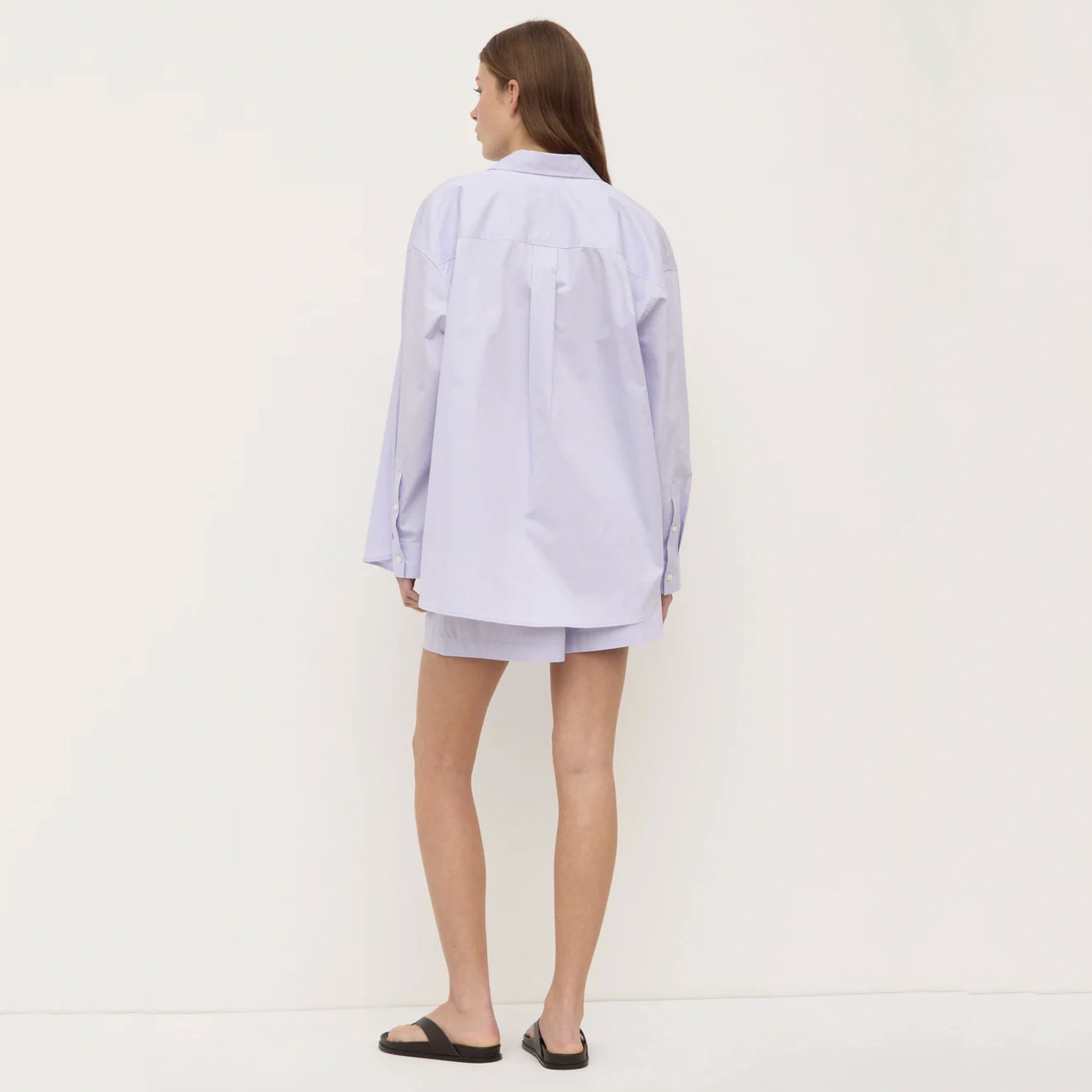 Woman wearing a light purple oversized shirt and shorts on a white background