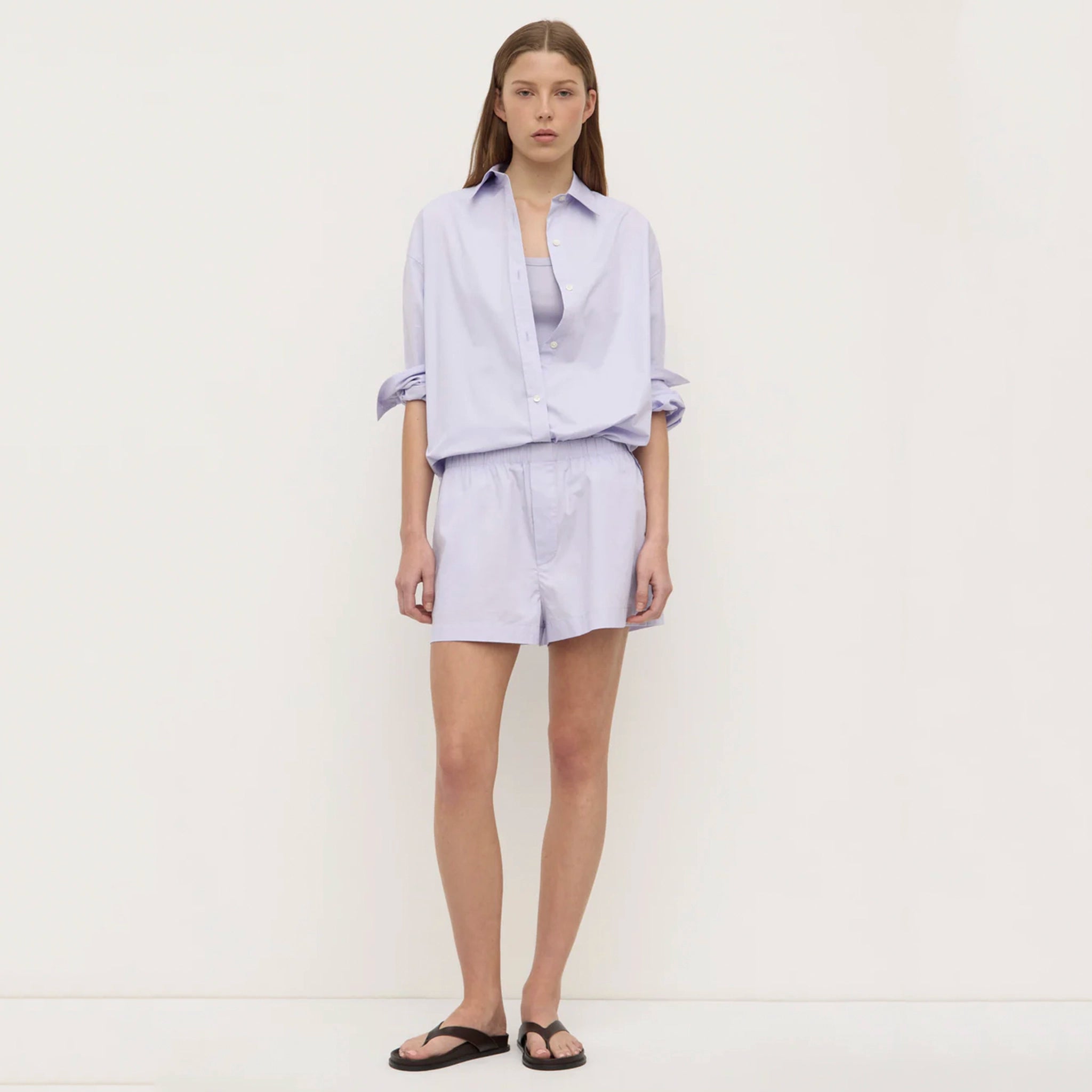 Woman wearing a light purple outfit with shorts on a white background