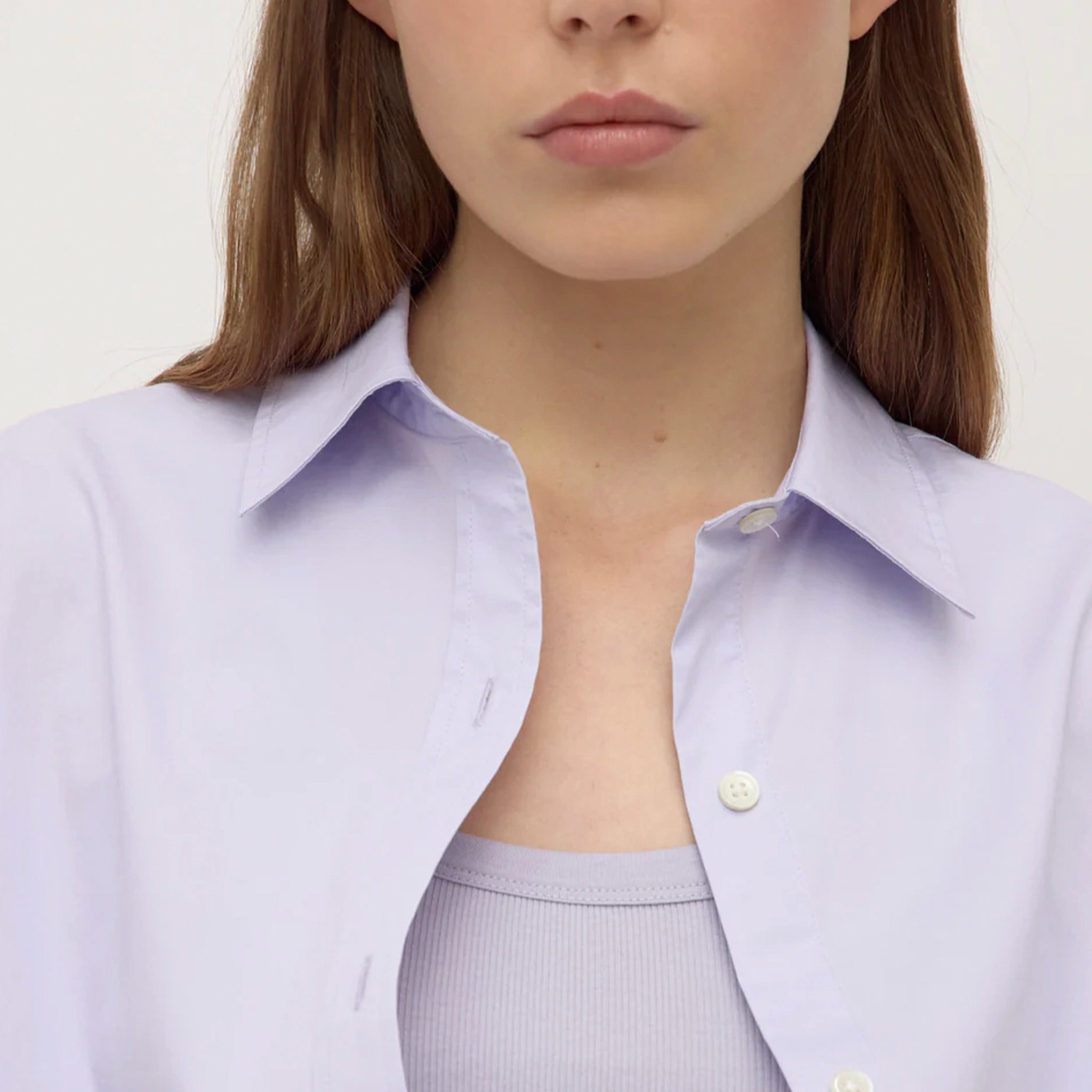 Person wearing a light purple shirt with a plain background