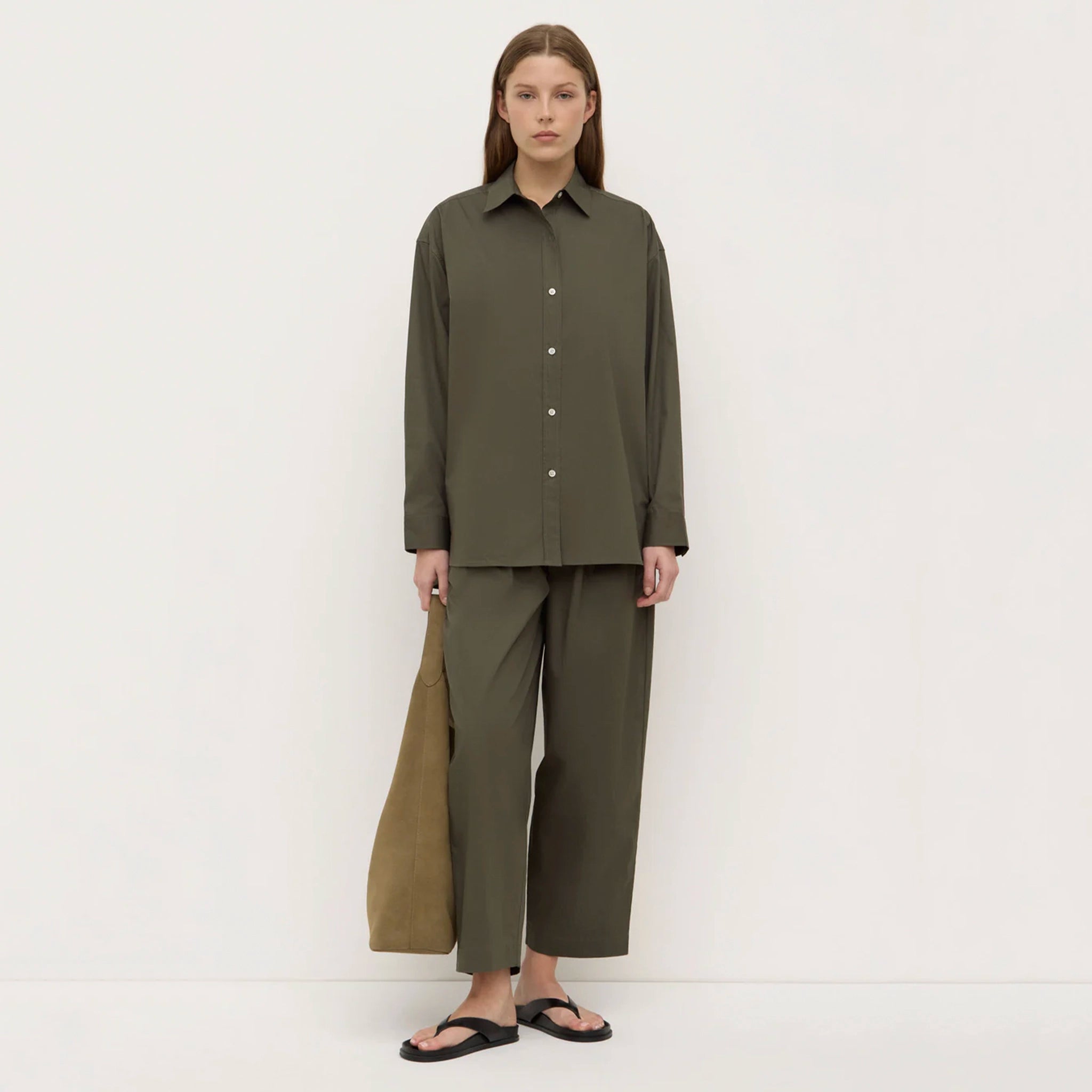 Woman wearing a green outfit standing against a white background
