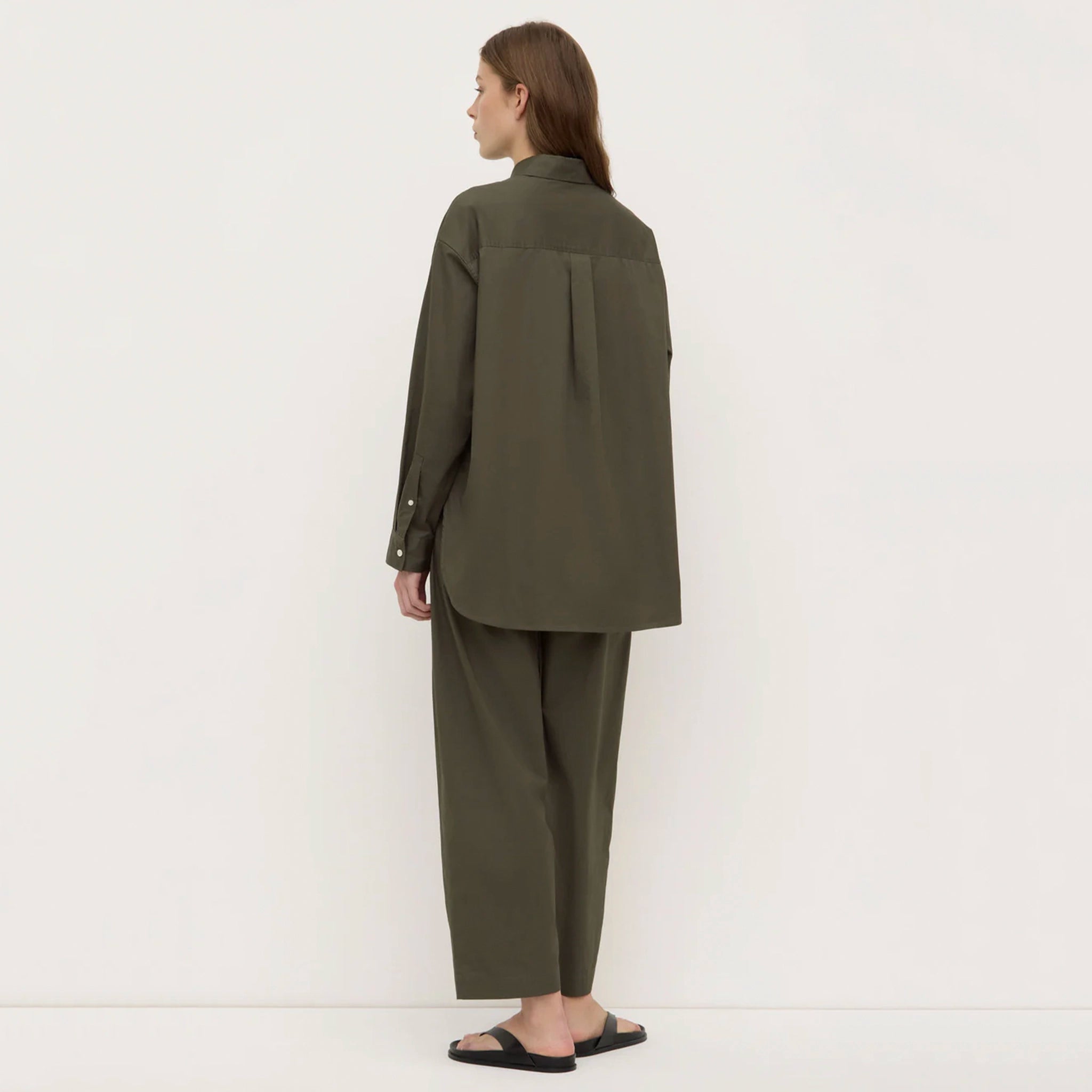 Person wearing an olive green outfit on a white background
