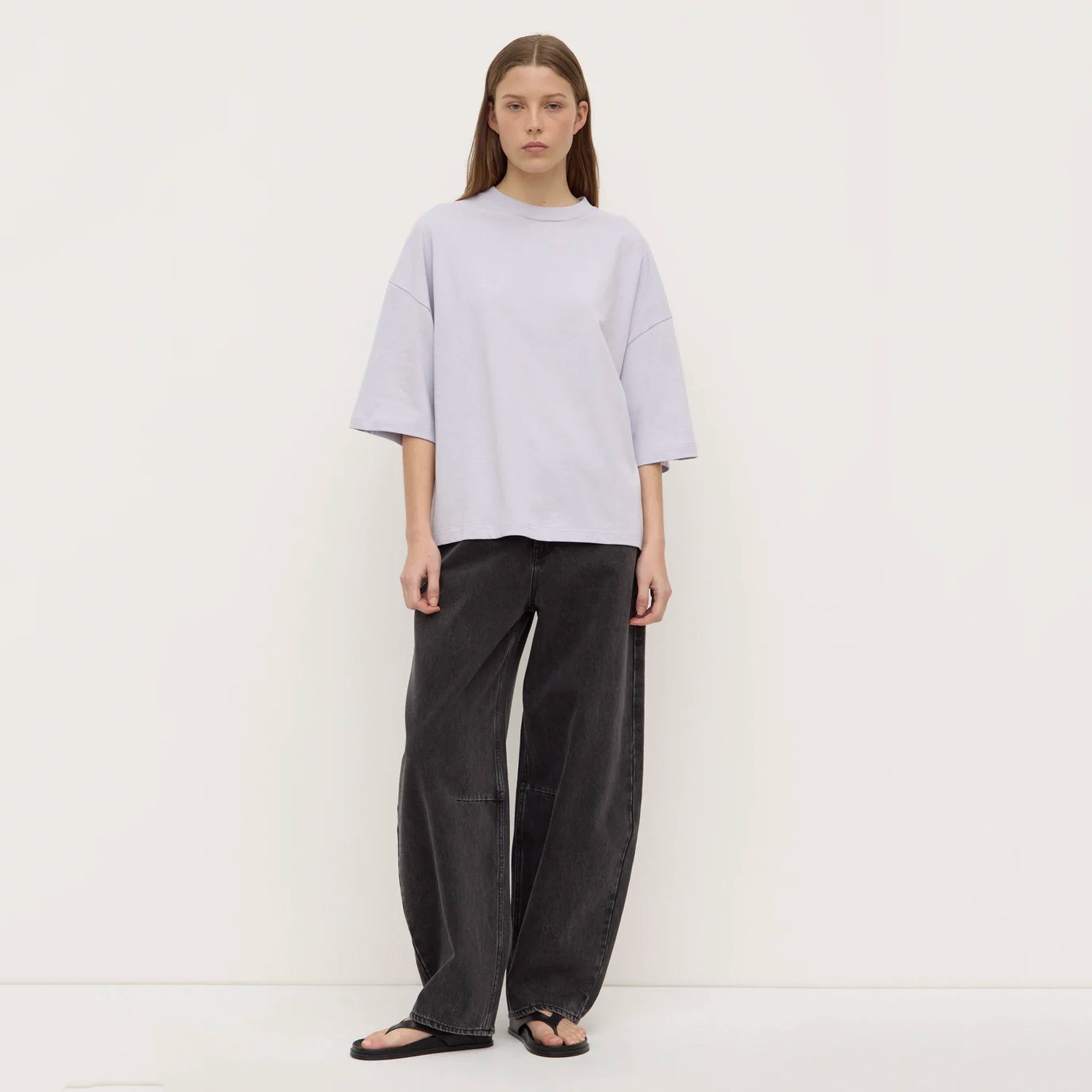 Person wearing a lilac top and dark pants against a white background