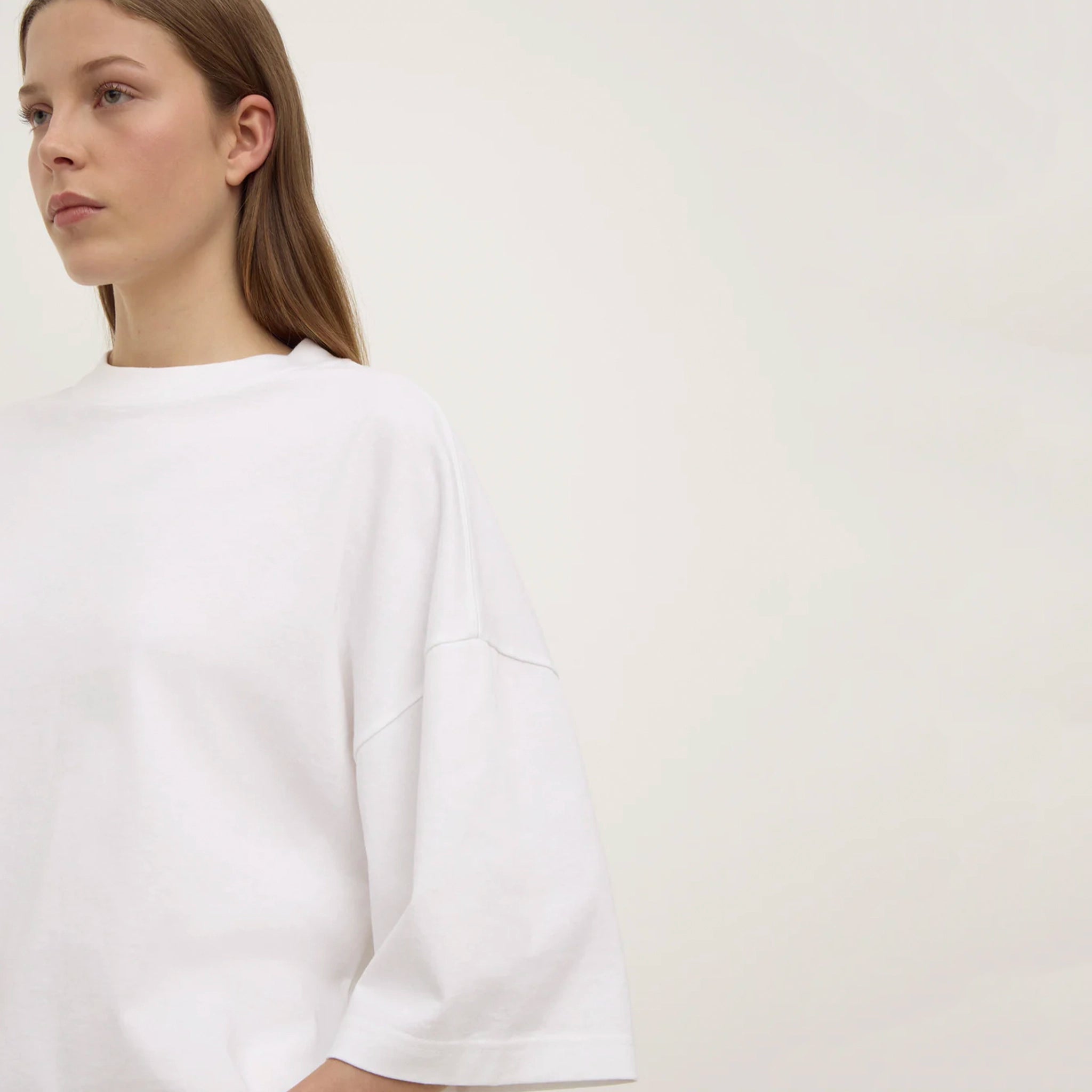 Woman wearing a white sweater against a plain background