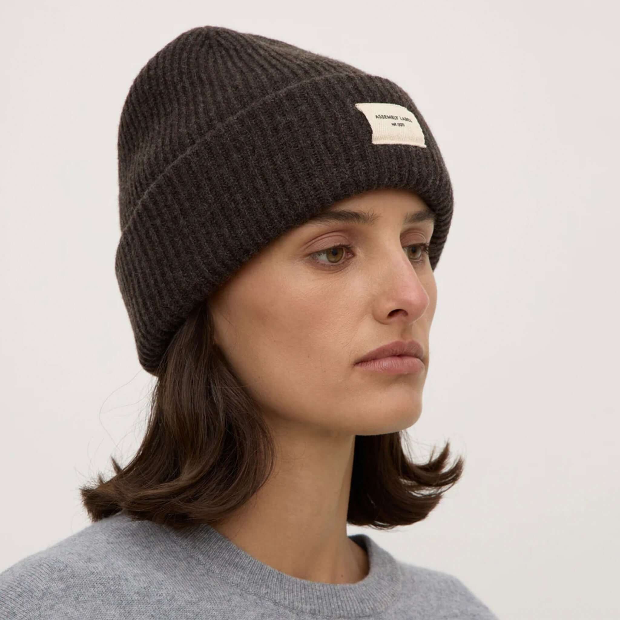 Assembly Label Merino Wool Rib Beanie - Ganache worn by a model, showcasing its classic rib design and warm, soft texture.