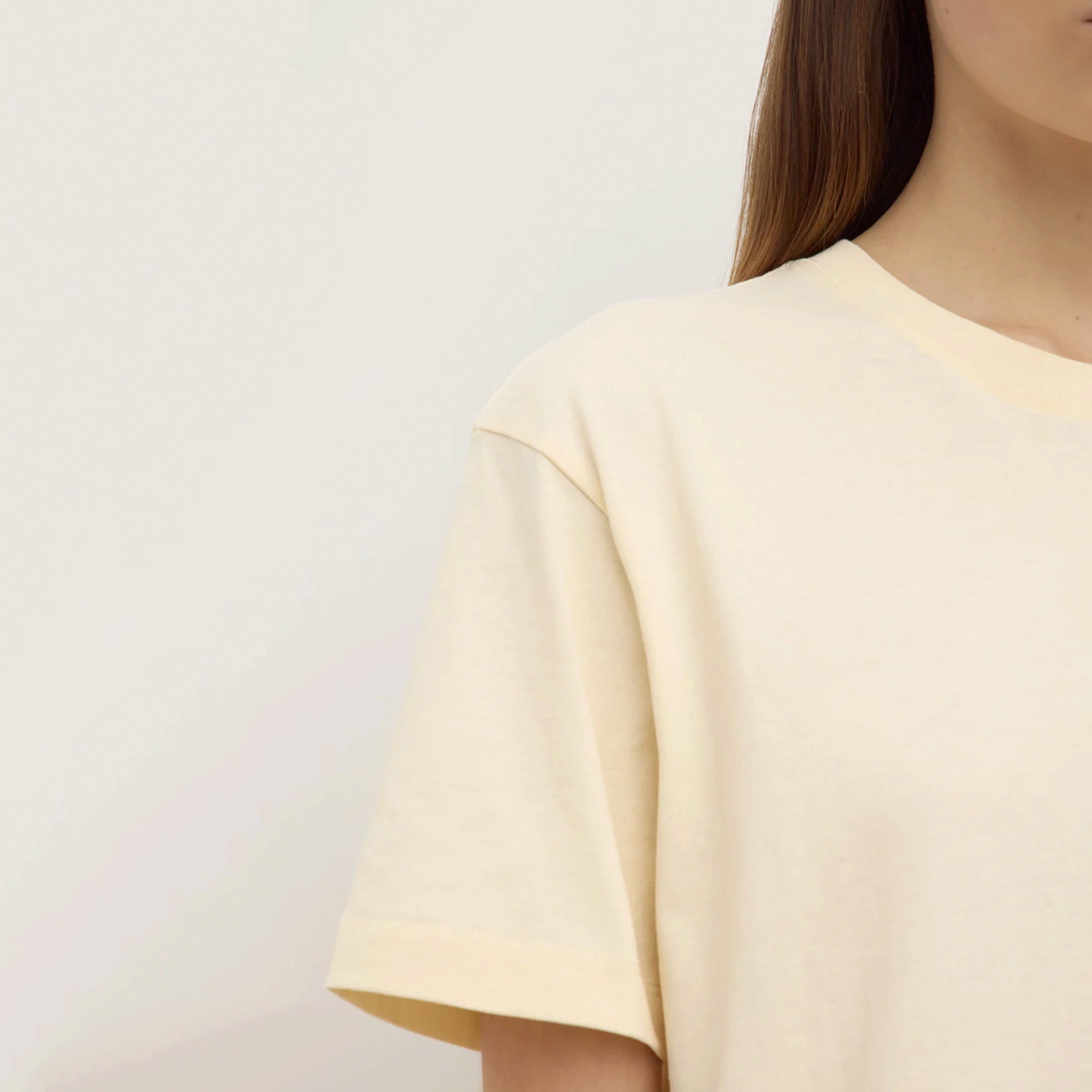 Person wearing a light yellow t-shirt against a plain background