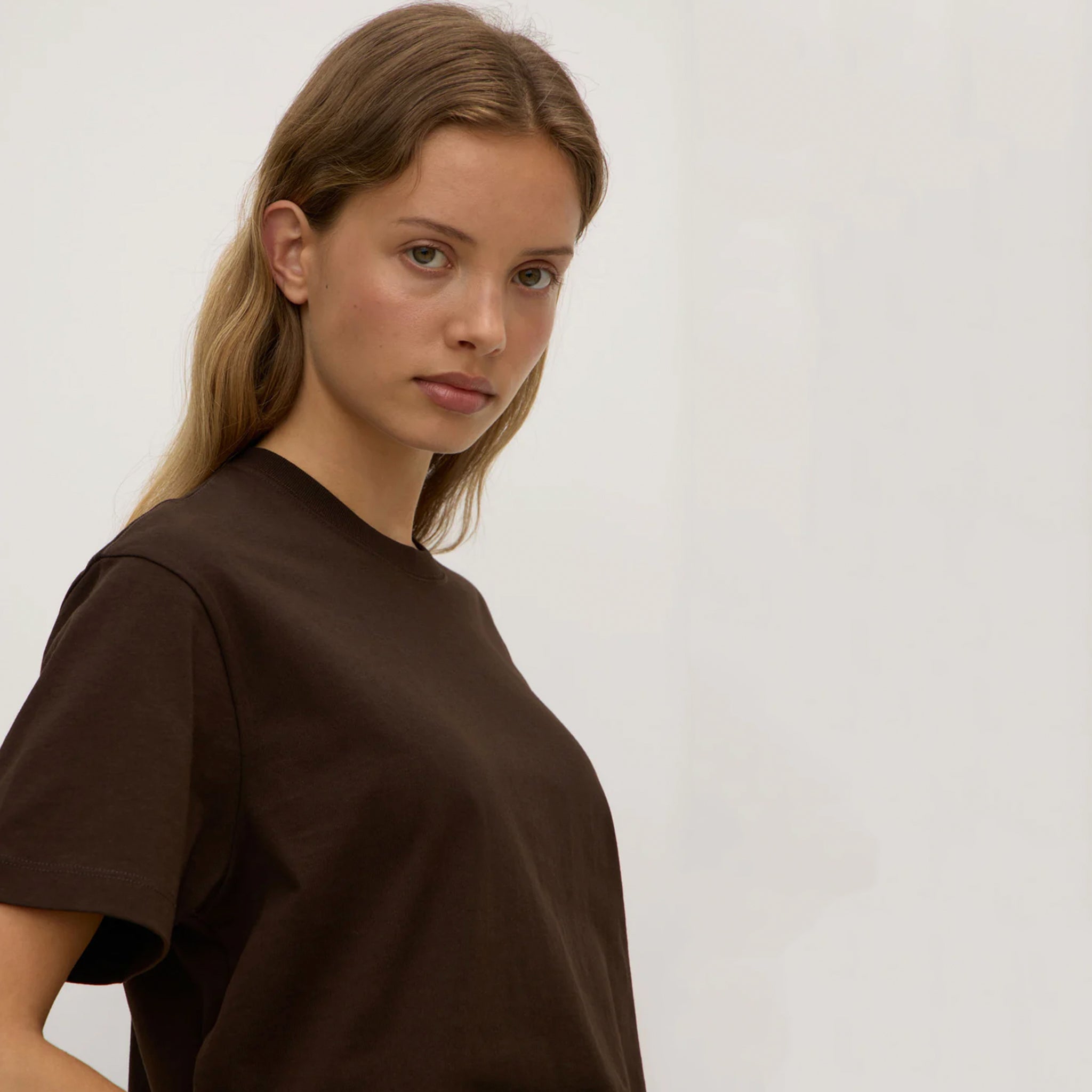 Woman wearing a brown t-shirt against a plain background