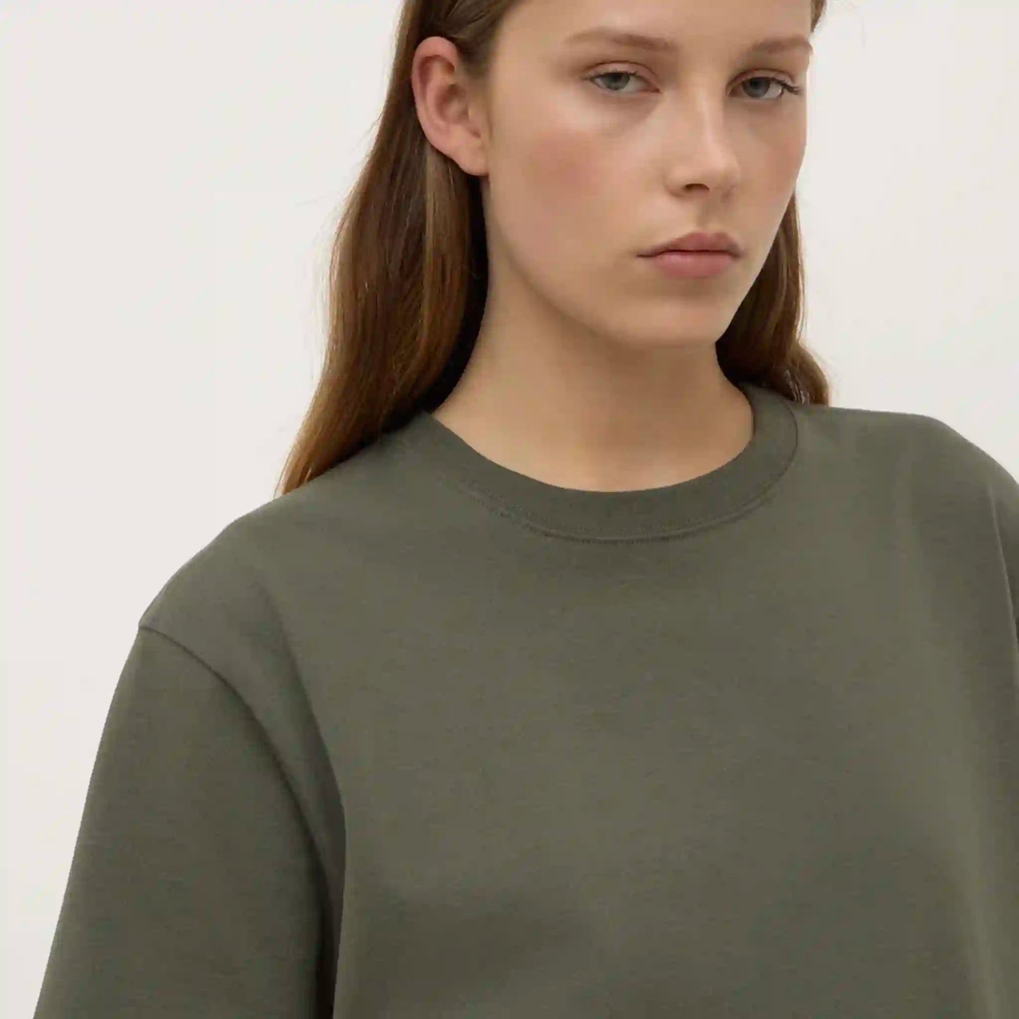 Person wearing a green sweater against a plain background