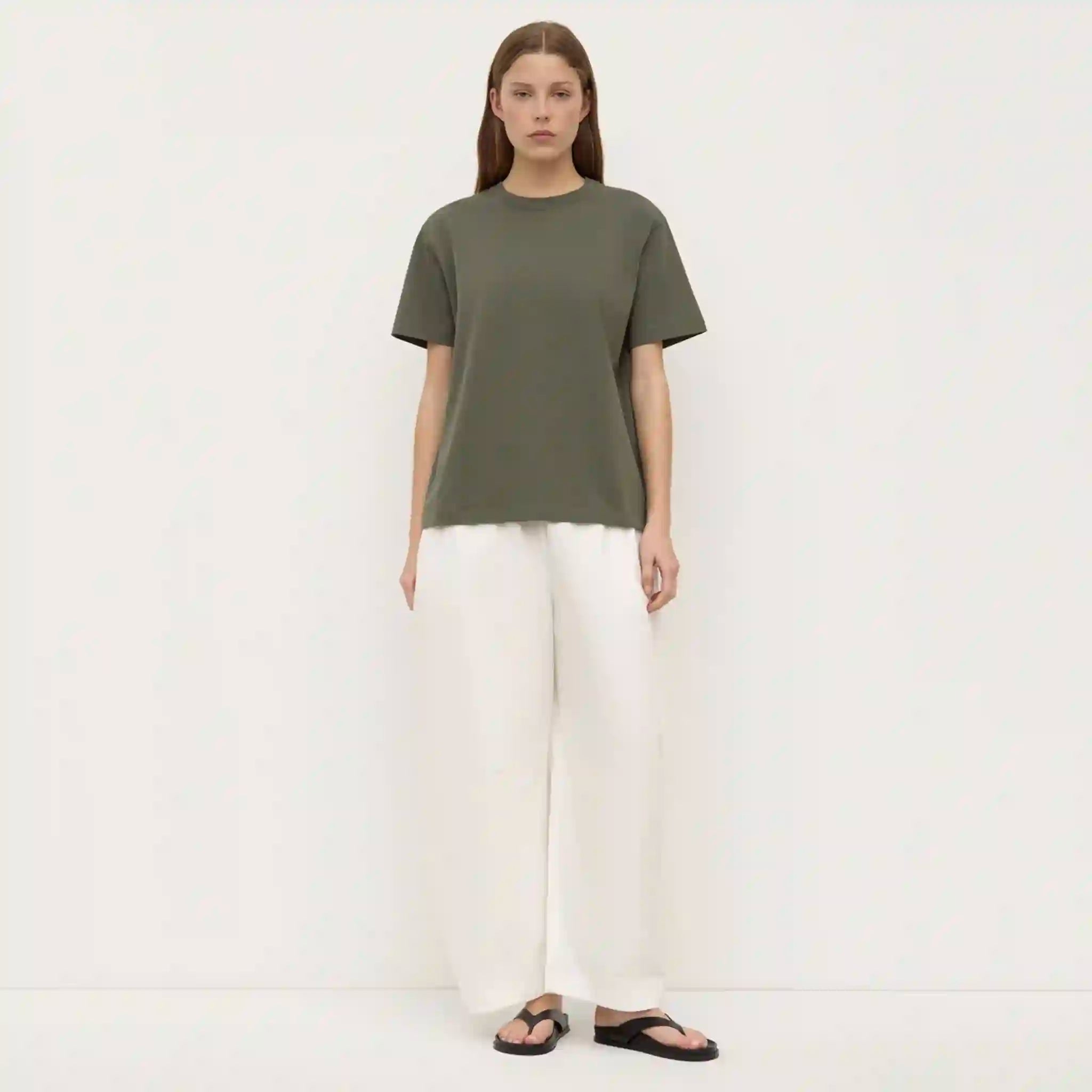 Person wearing a green t-shirt and white pants on a white background