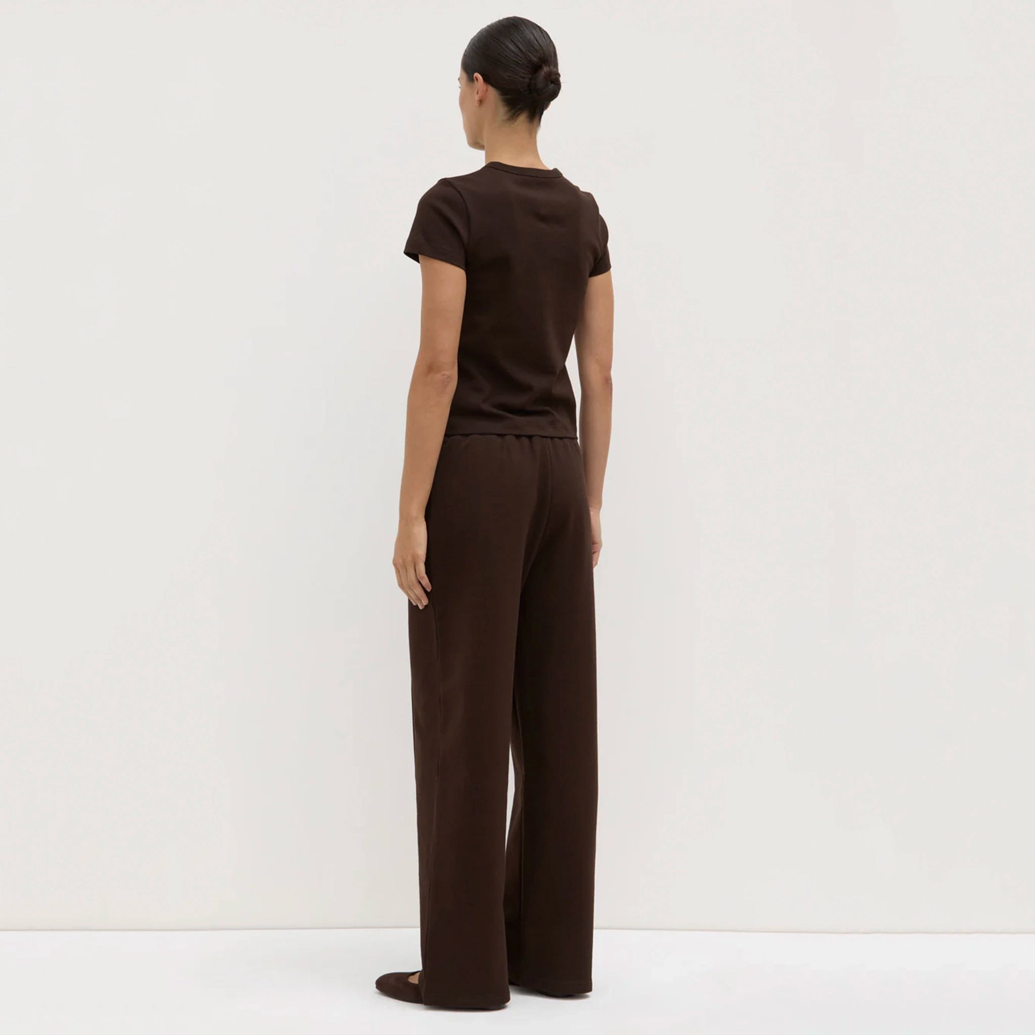 Woman wearing a brown outfit standing against a white background