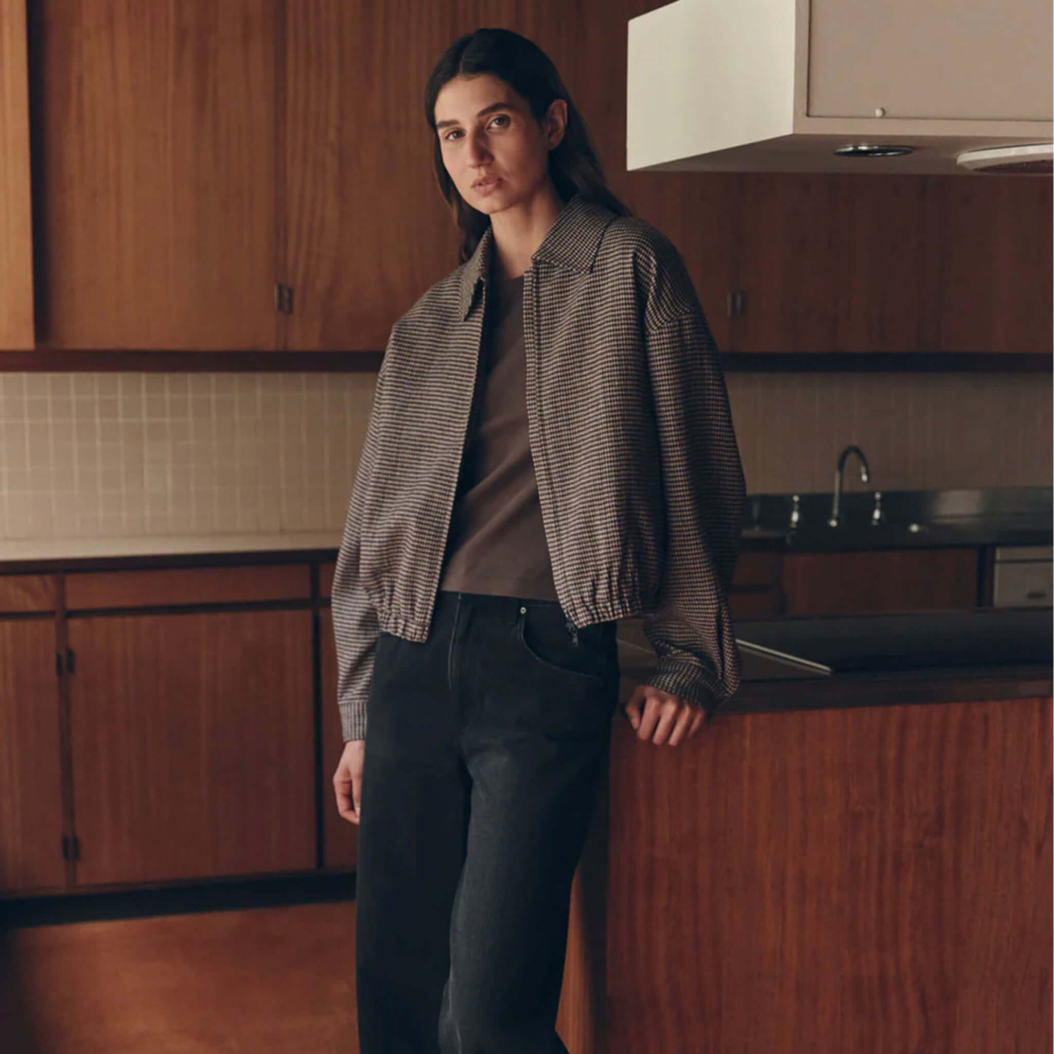 Model wearing a brown black check wool jacket by Assembly Label in a stylish indoor setting.