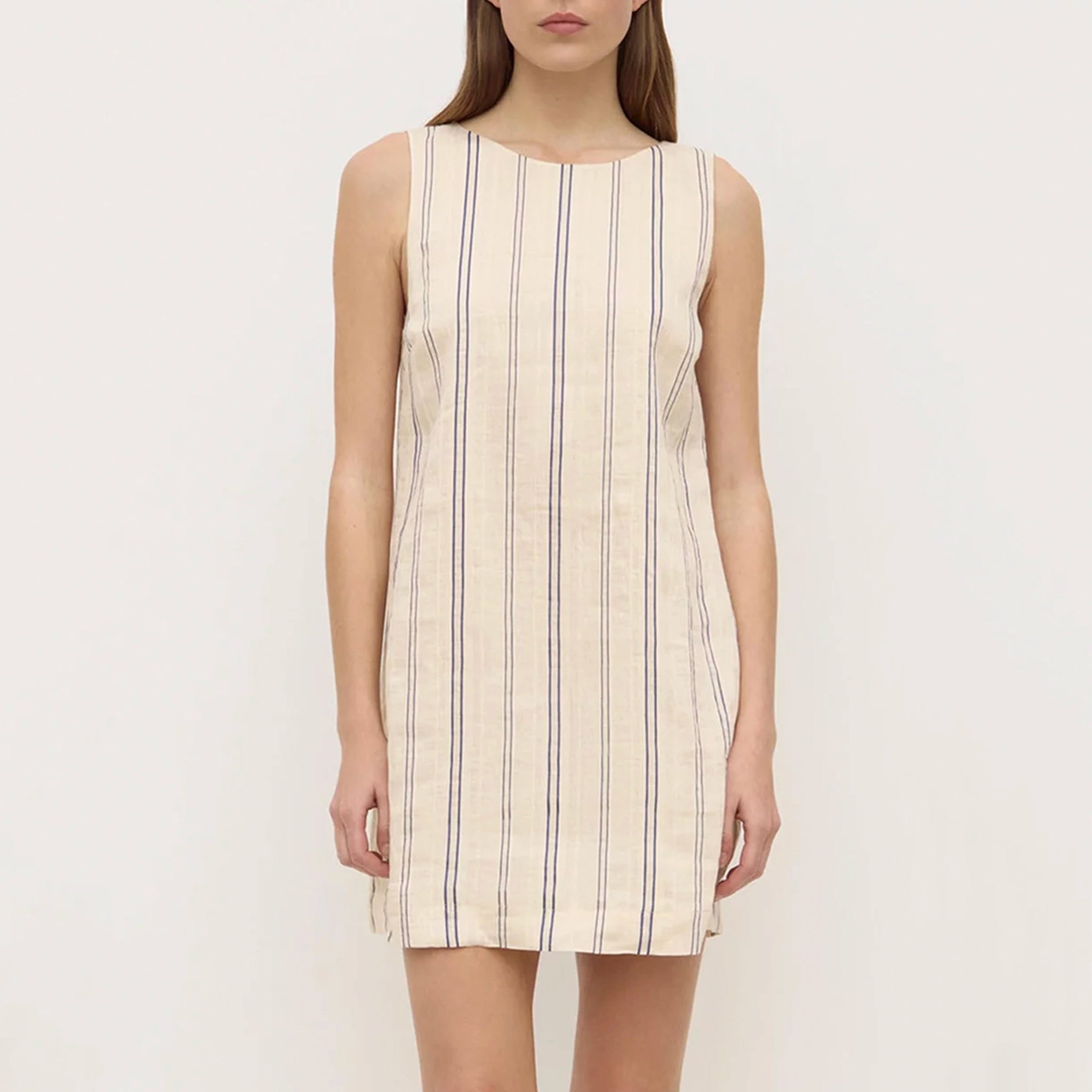 Woman wearing a sleeveless dress with vertical stripes on a plain background