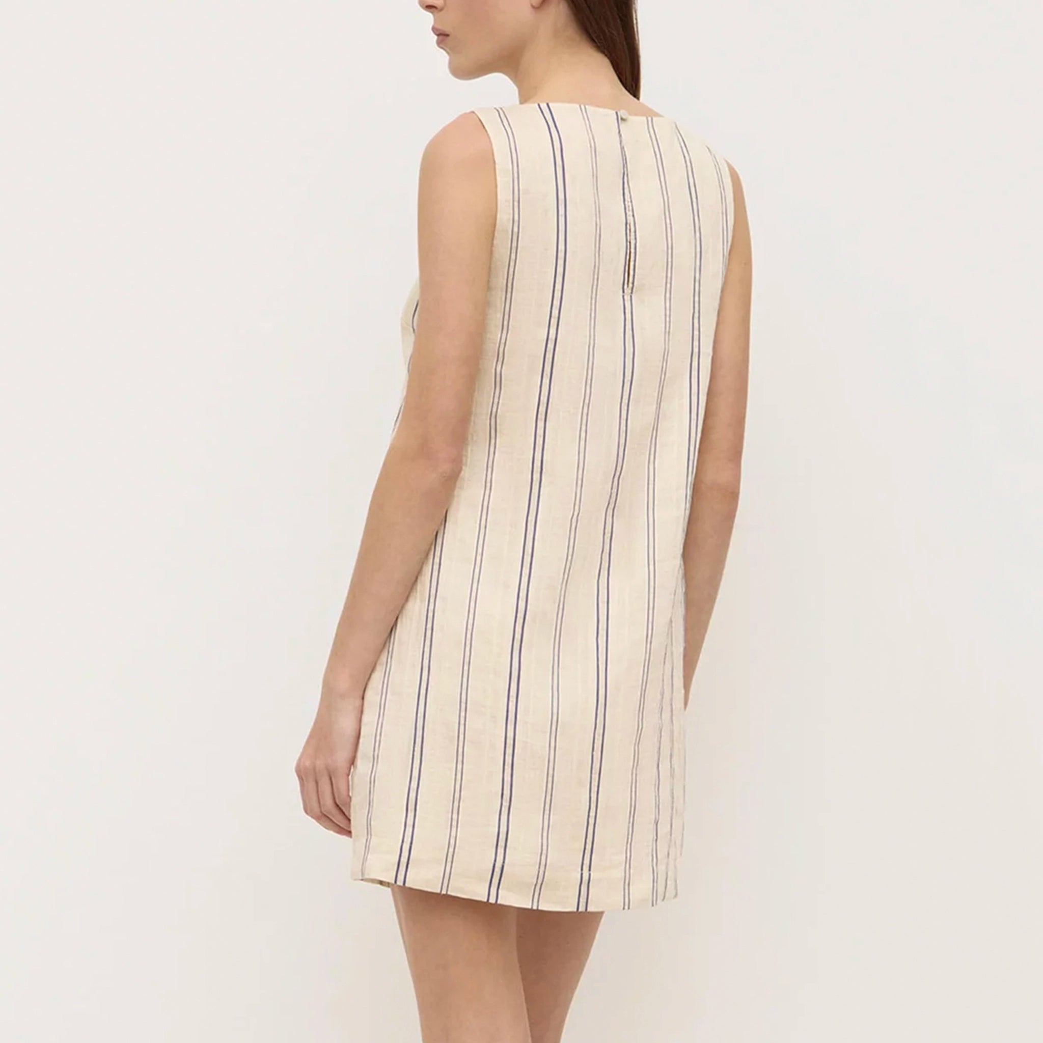 Woman wearing a sleeveless dress with vertical stripes on a plain background