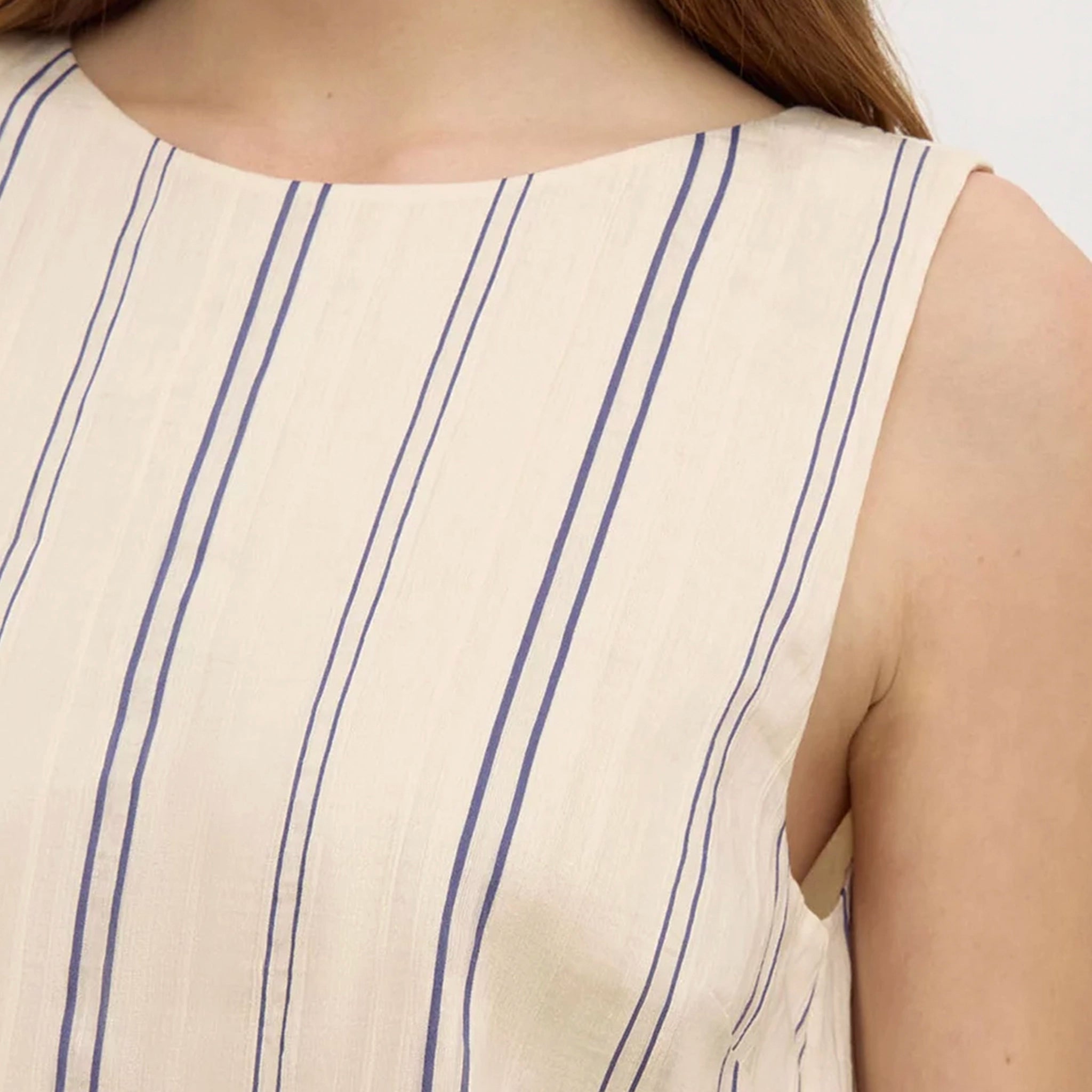 Close-up of a sleeveless dress with blue vertical stripes on a plain background