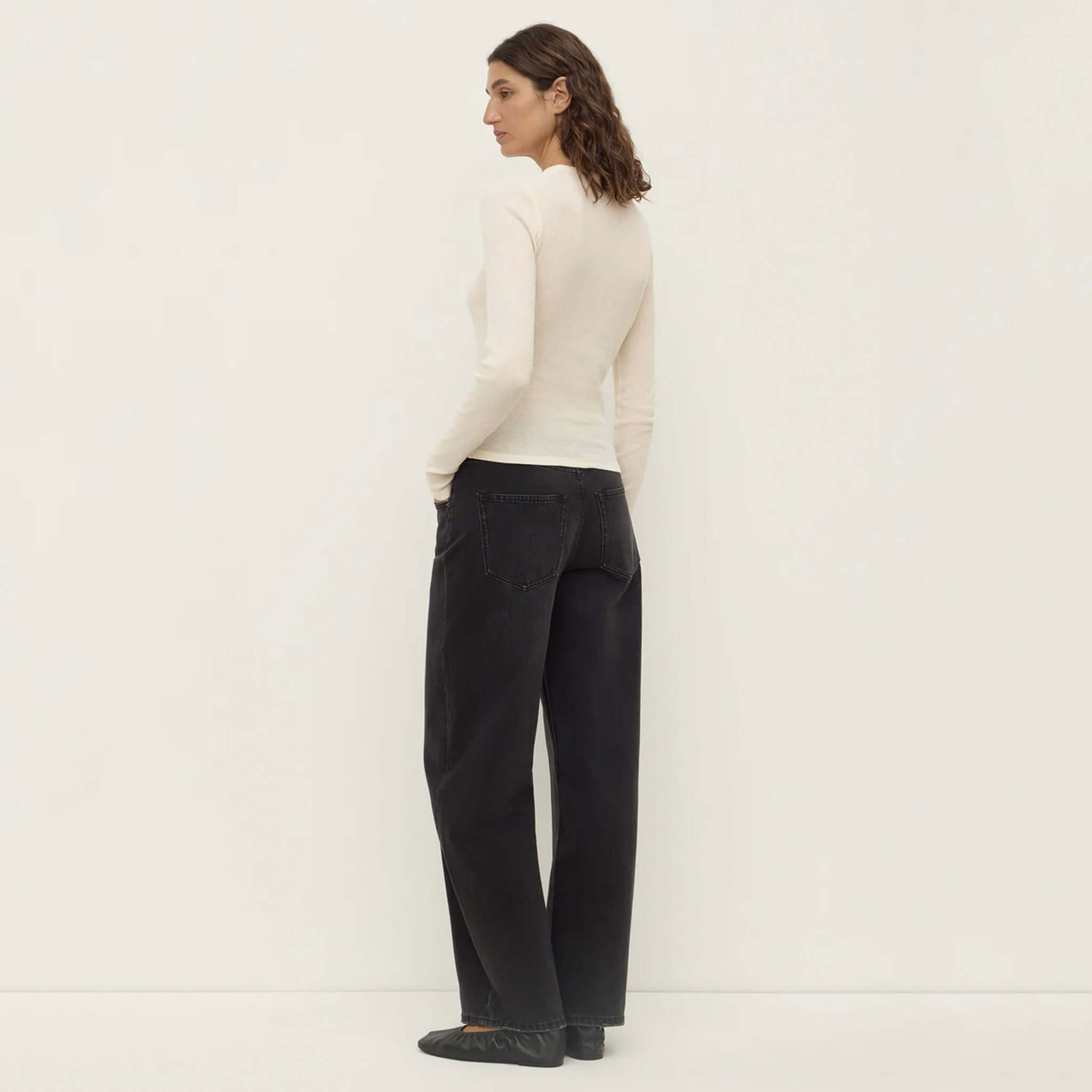 Alt Tag: Assembly Label Zali Long Sleeve Tee - Cream on model, back view of fitted ribbed cotton crew neck long sleeve top with black jeans