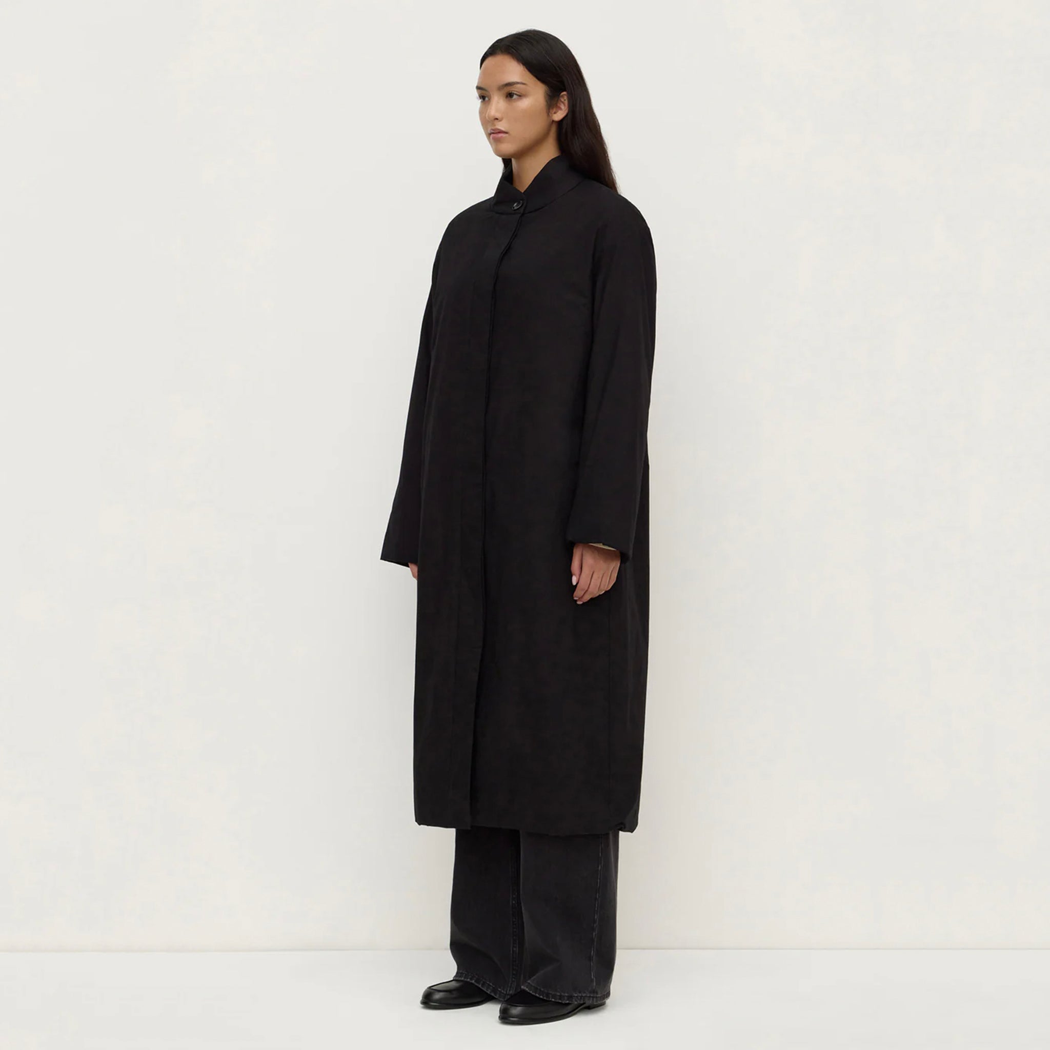 Assembly Label Zoie Padded Coat - Black displayed on a model in a side view, showcasing its sleek silhouette.