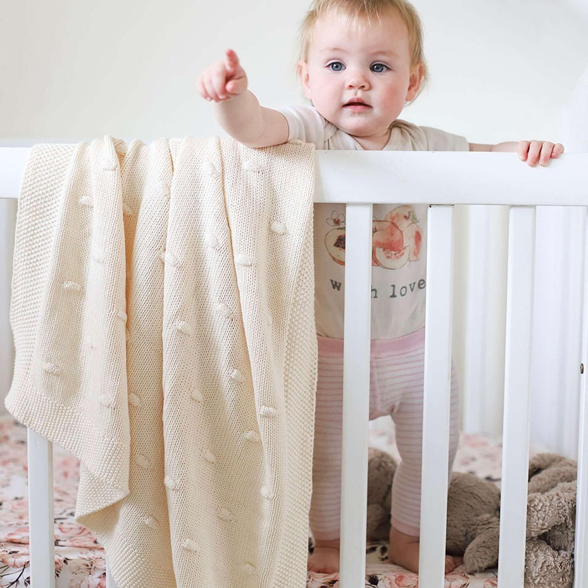 Baby Cotton Marshmallow Blanket - Natural draped over crib with baby reaching out.