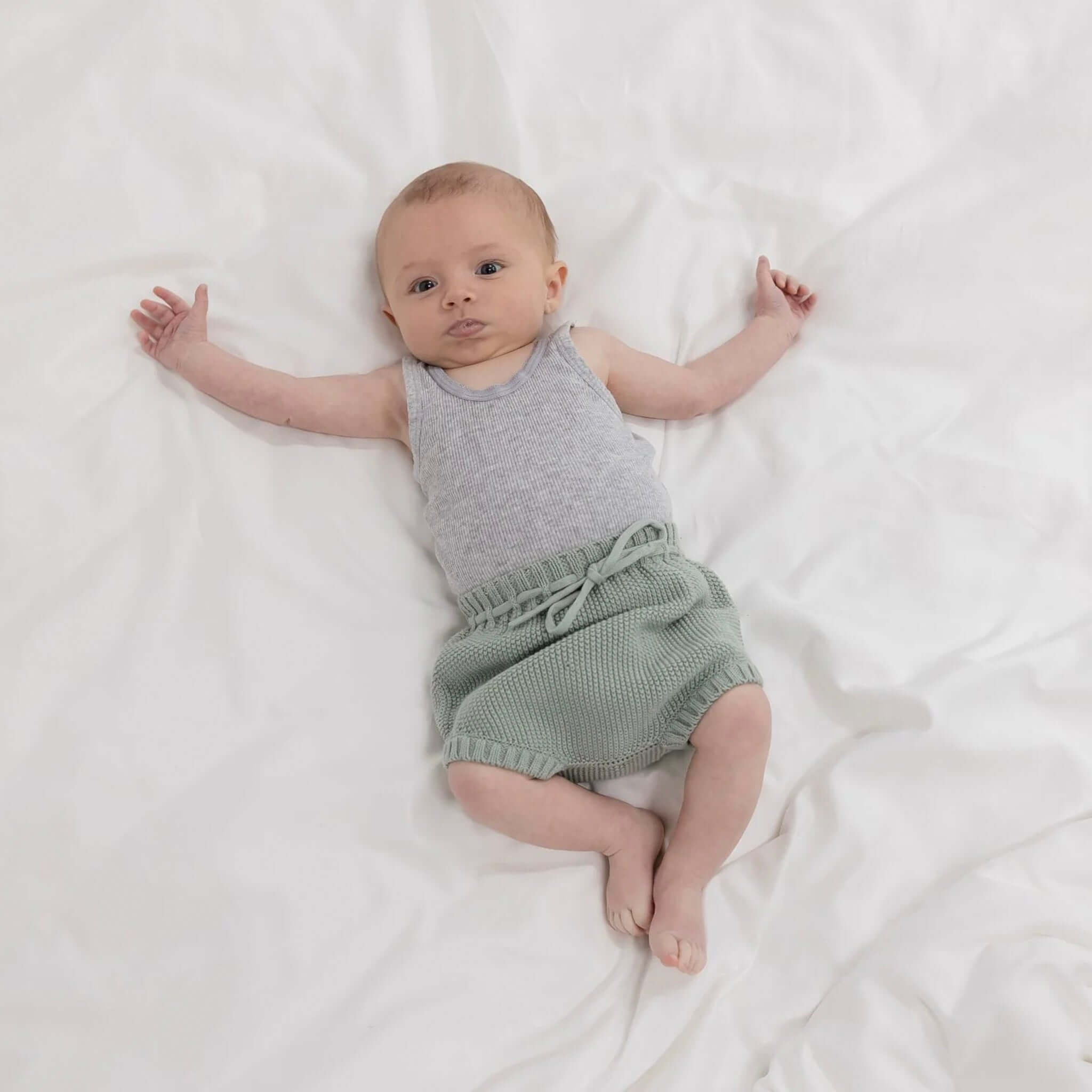 Baby Cotton Noah Bloomer - Duck Egg styled on an adorable baby laying on a soft white blanket.