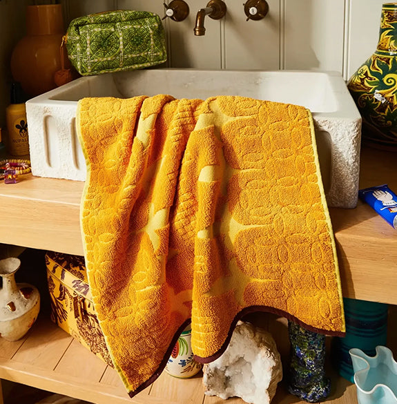 Yellow textured towel draped over a sink in a bathroom setting
