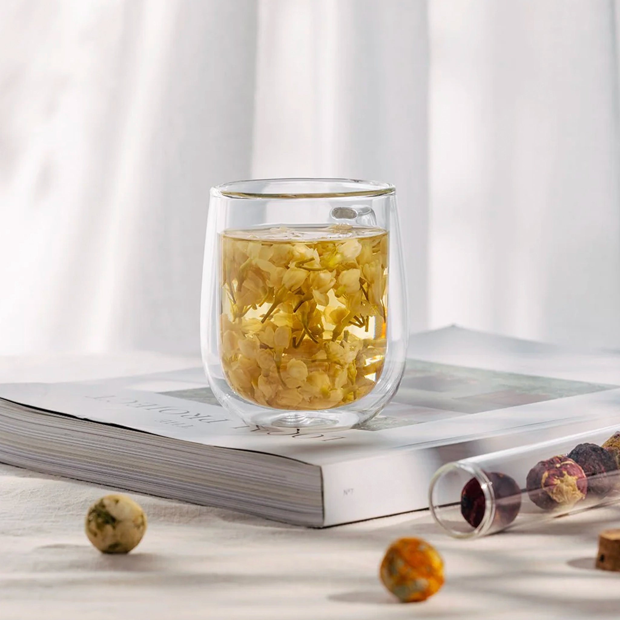 Clear glass with tea leaves on a white surface with a white curtain background