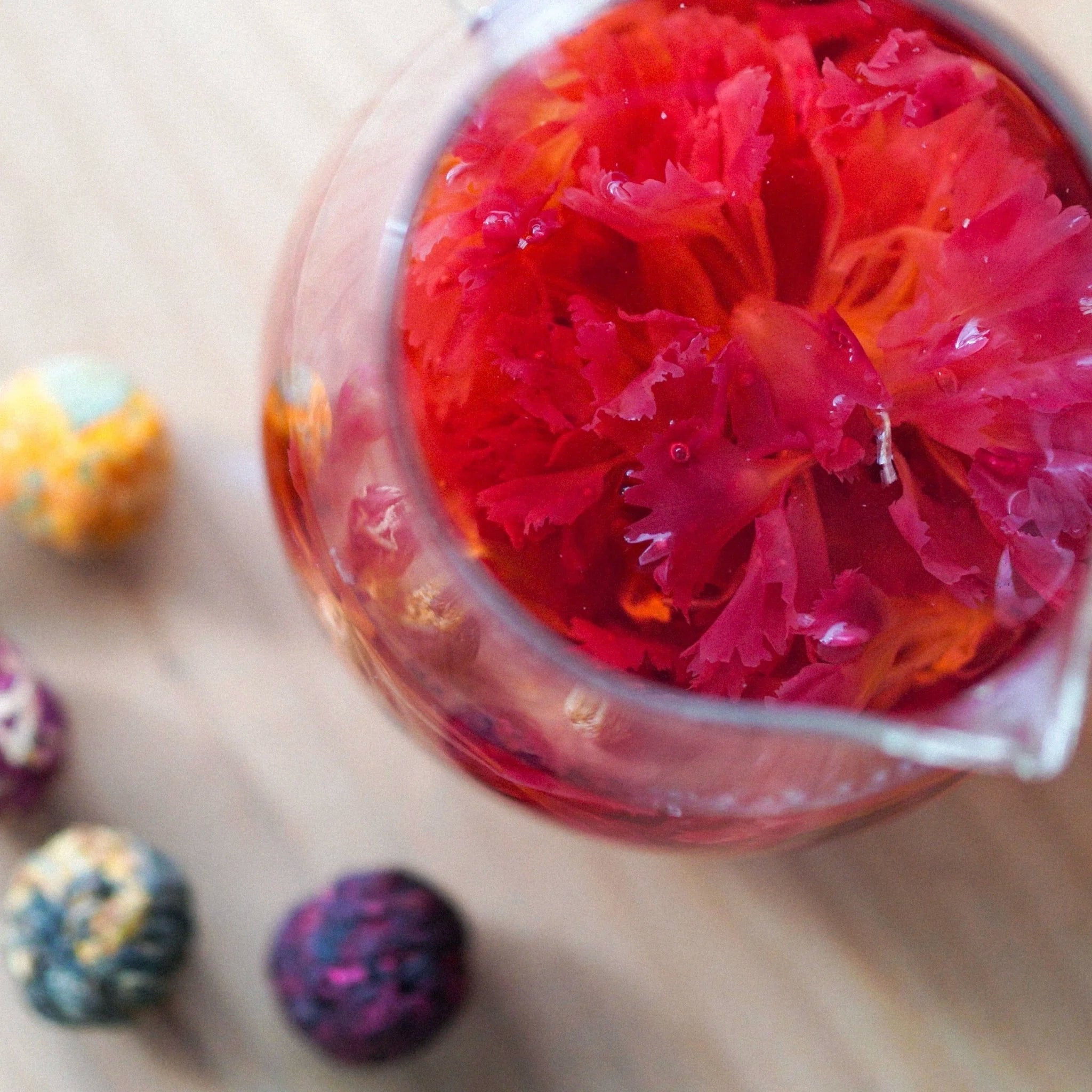Clear container with pink floral arrangement on a wooden surface with colorful balls.