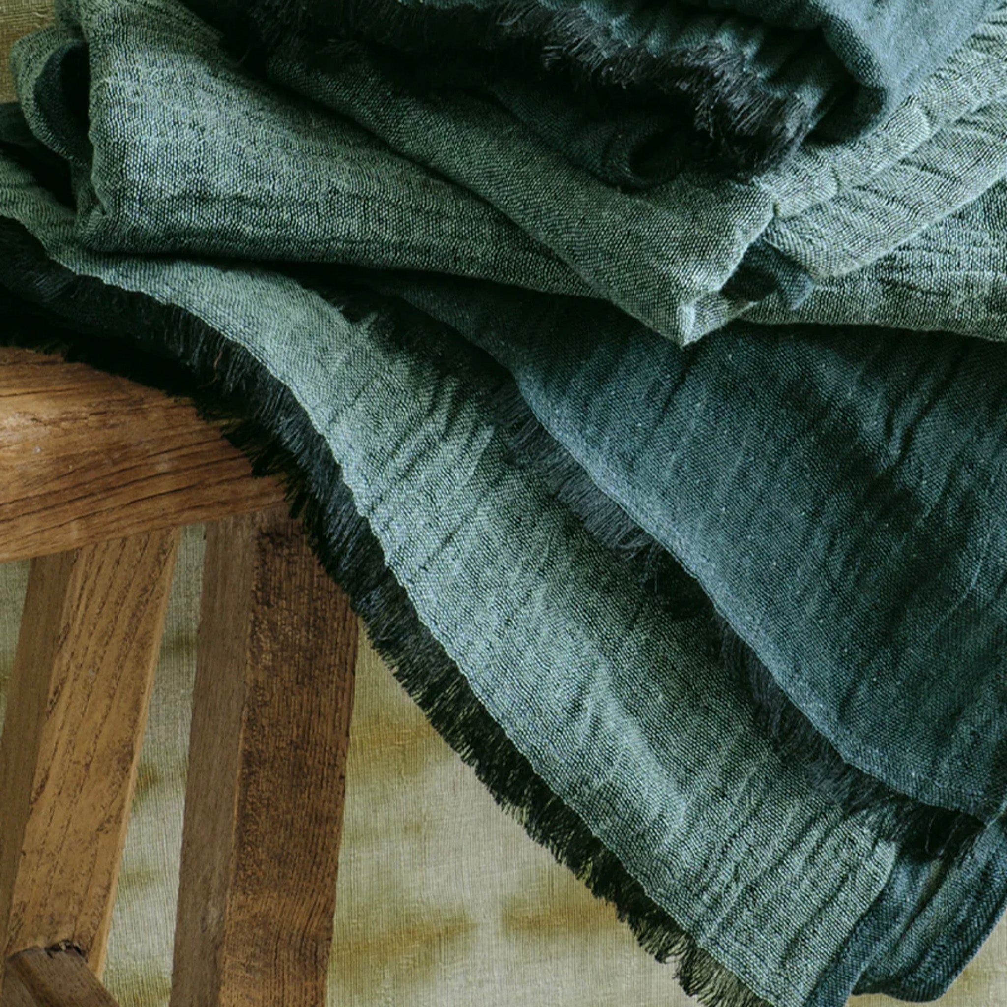 Stack of green textured towels on a wooden stool