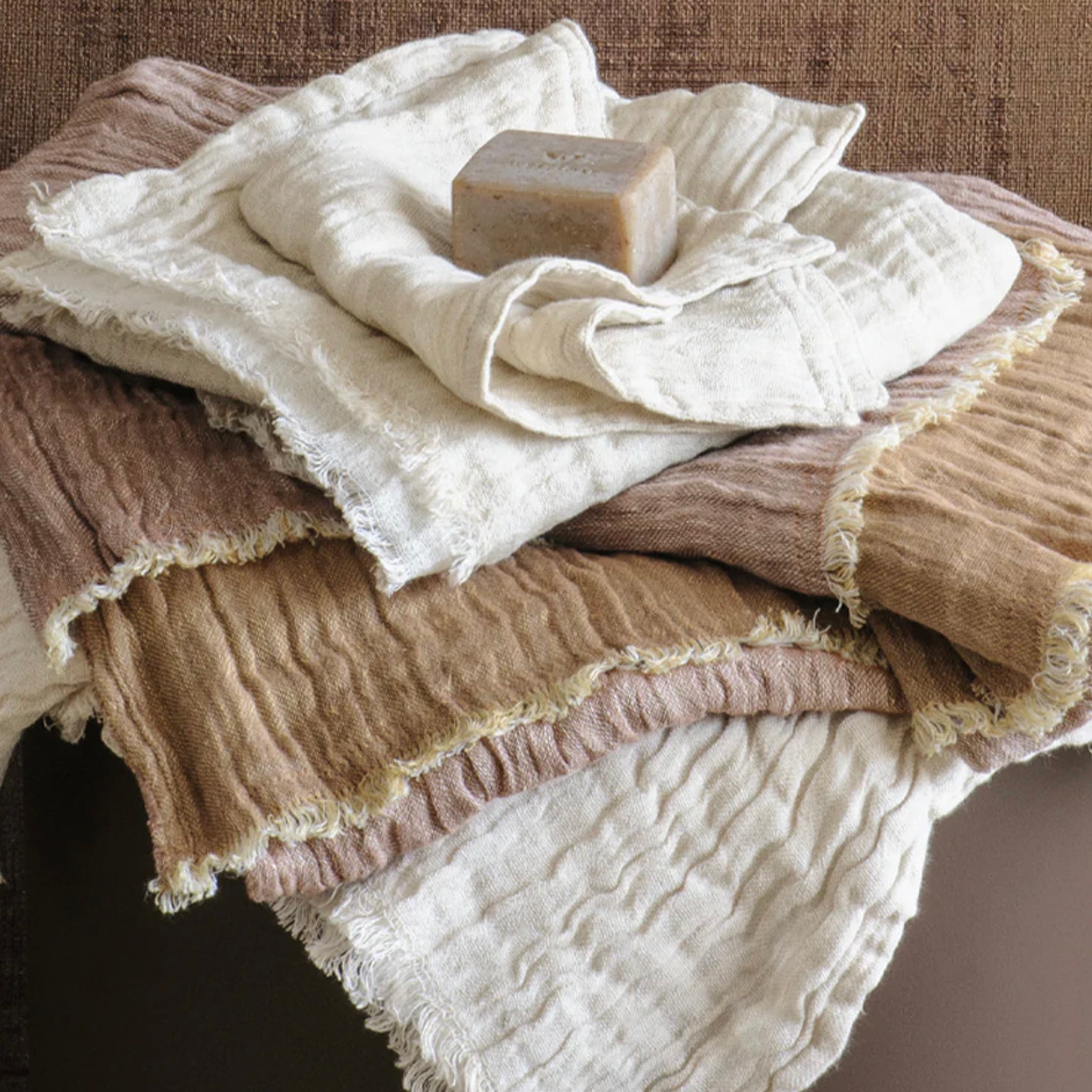Stack of textured towels with a bar of soap on a wooden surface