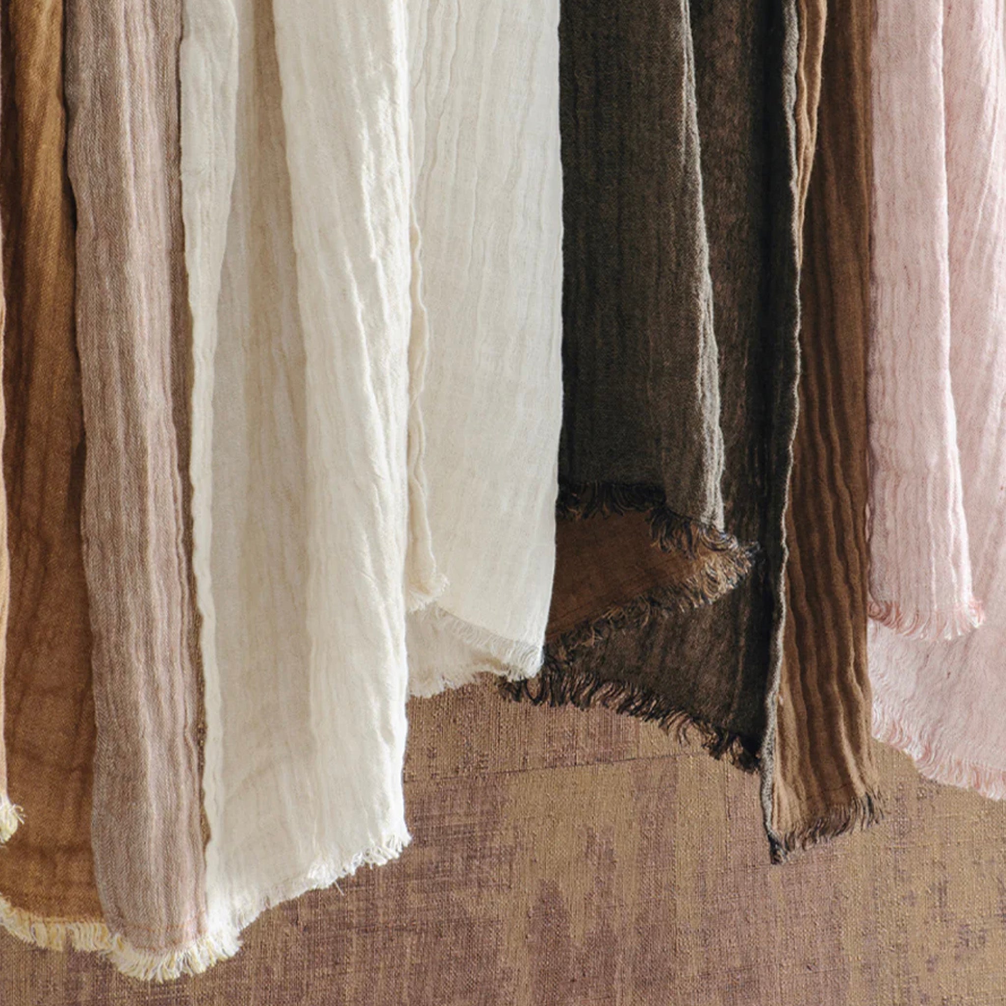 Close-up of various textured hand towels in neutral colors on a textured surface.