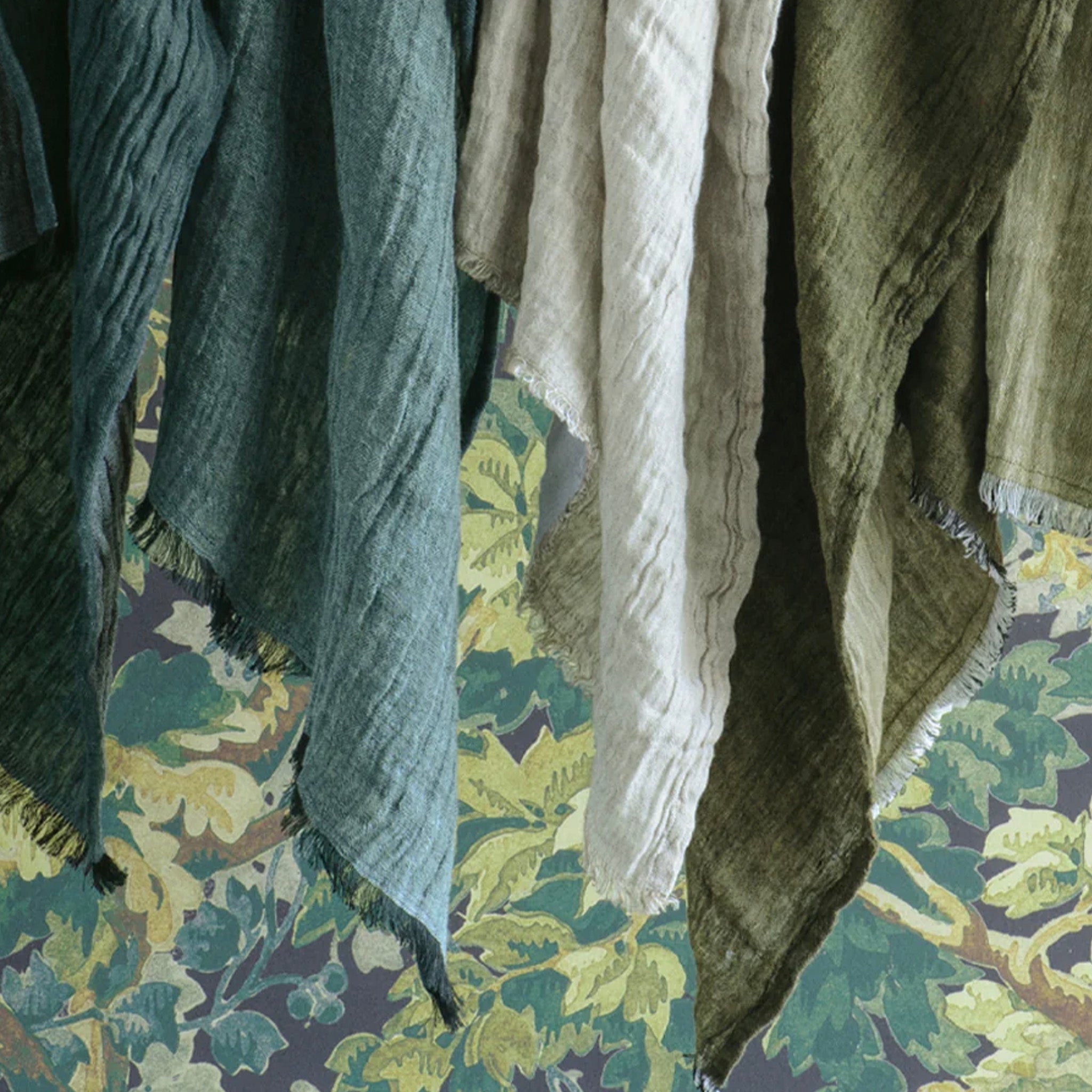 Textured hand towels in green and brown on a floral-patterned fabric background
