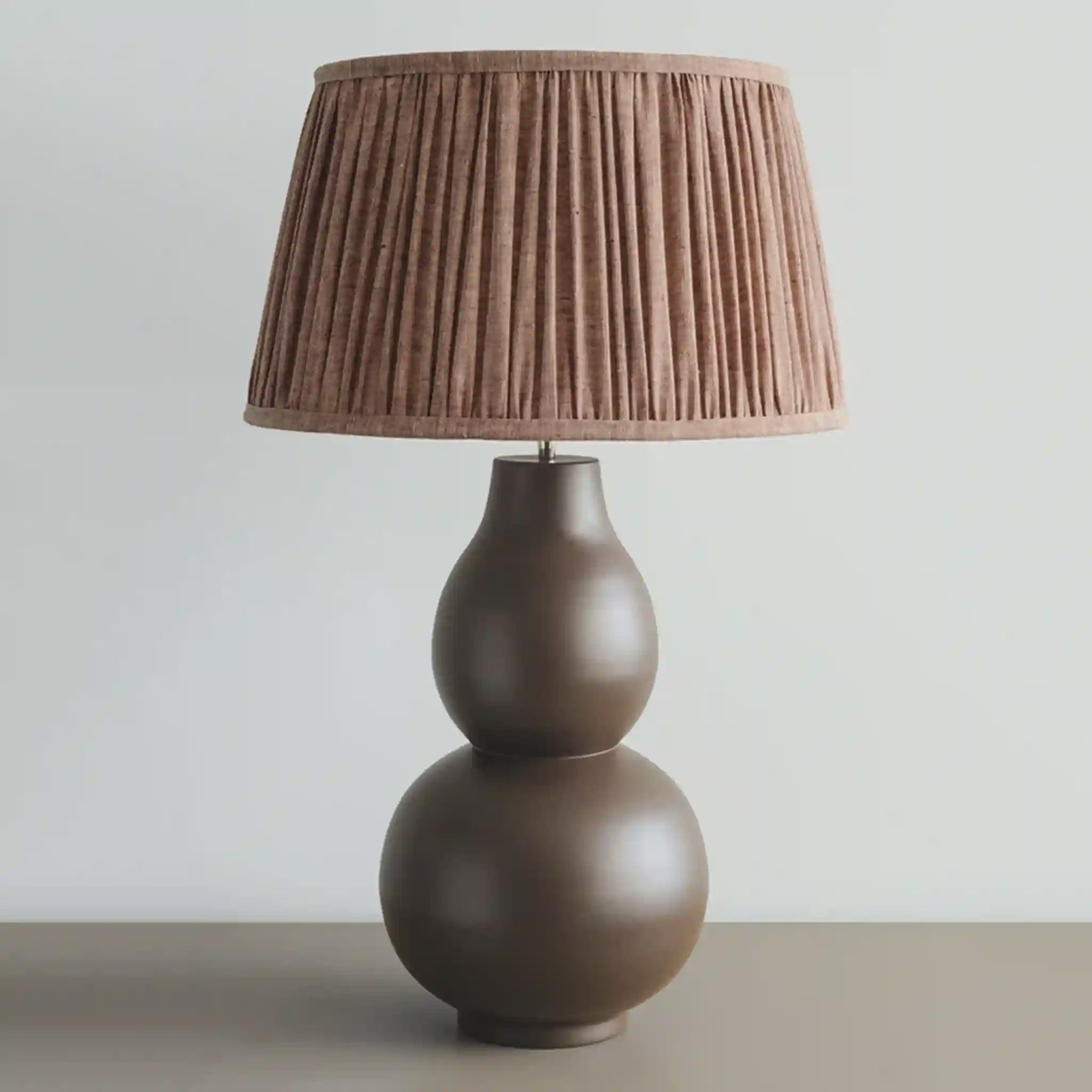 Brown table lamp with pleated shade on a neutral background