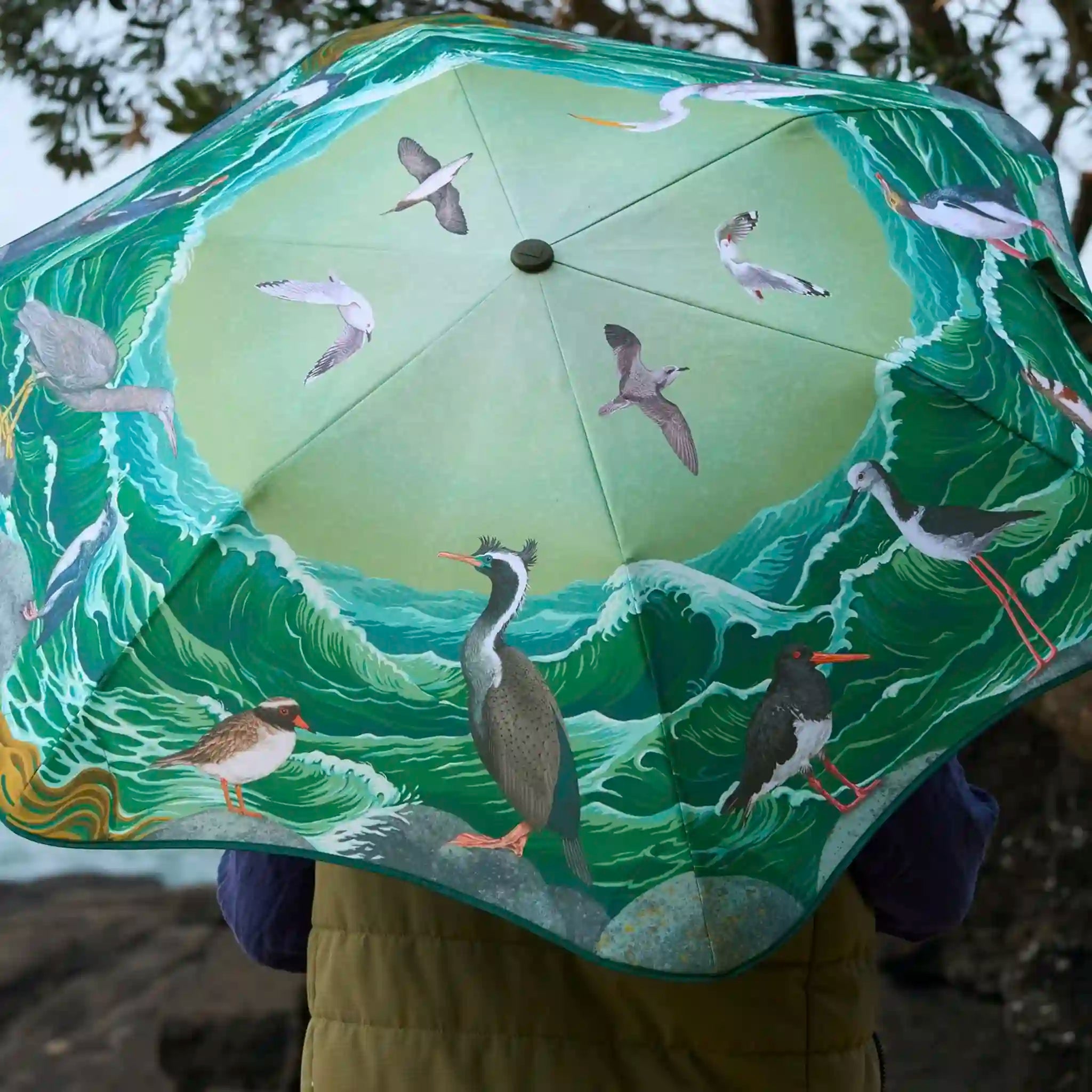 Umbrella with bird design held by a person in a snowy landscape