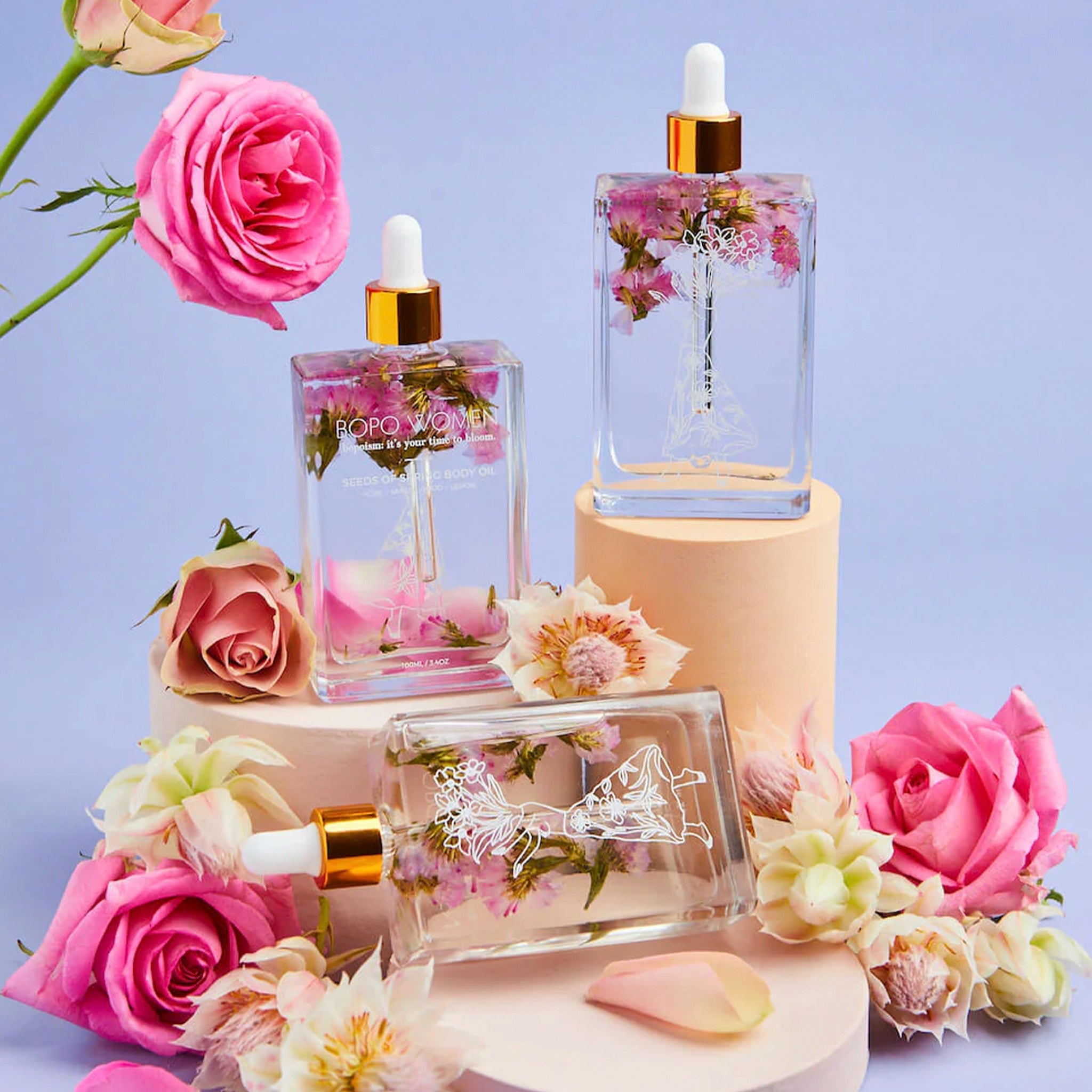Bottles of body oil with floral design and gold cap 