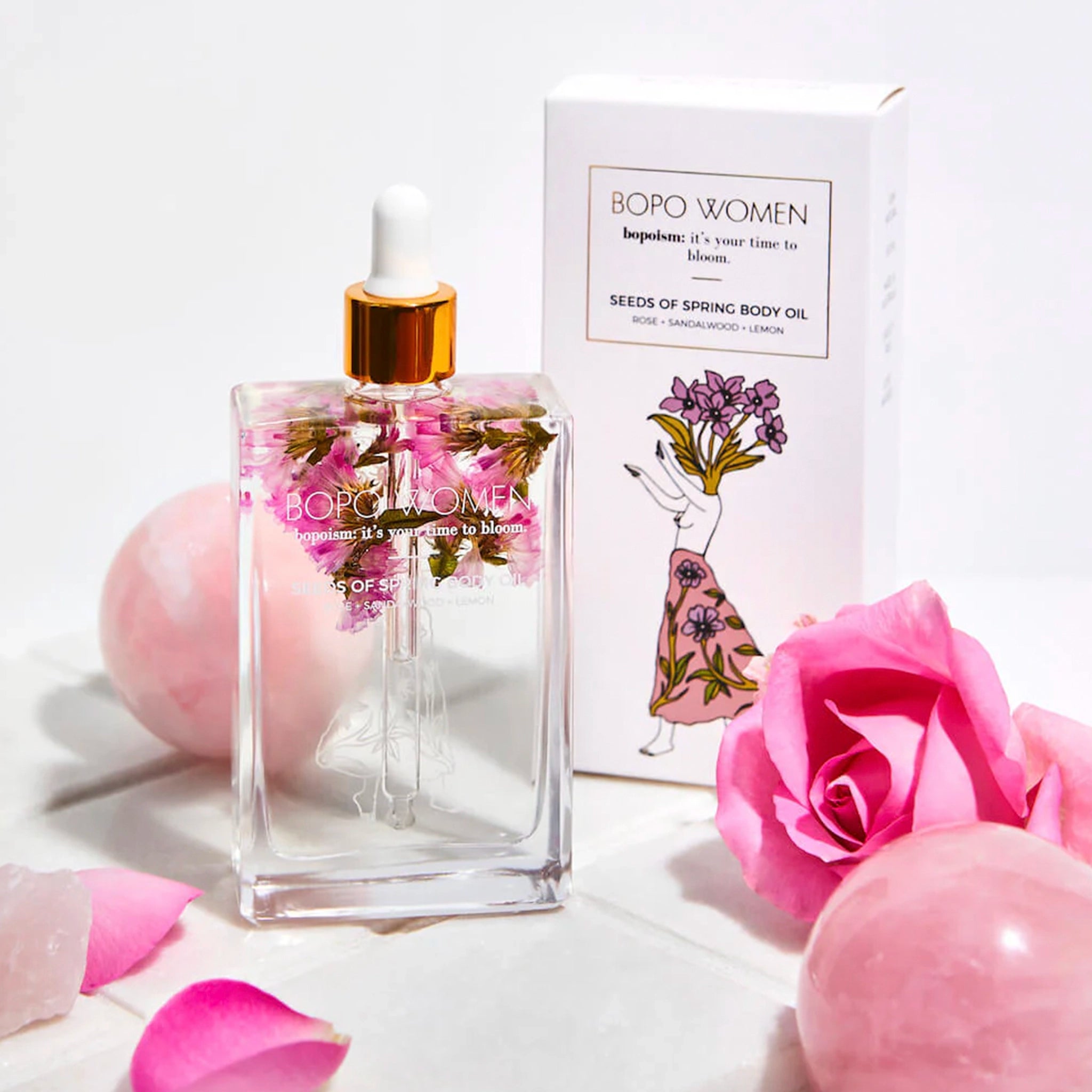 BOPO WOMEN perfume bottle with packaging and pink flowers on a light background