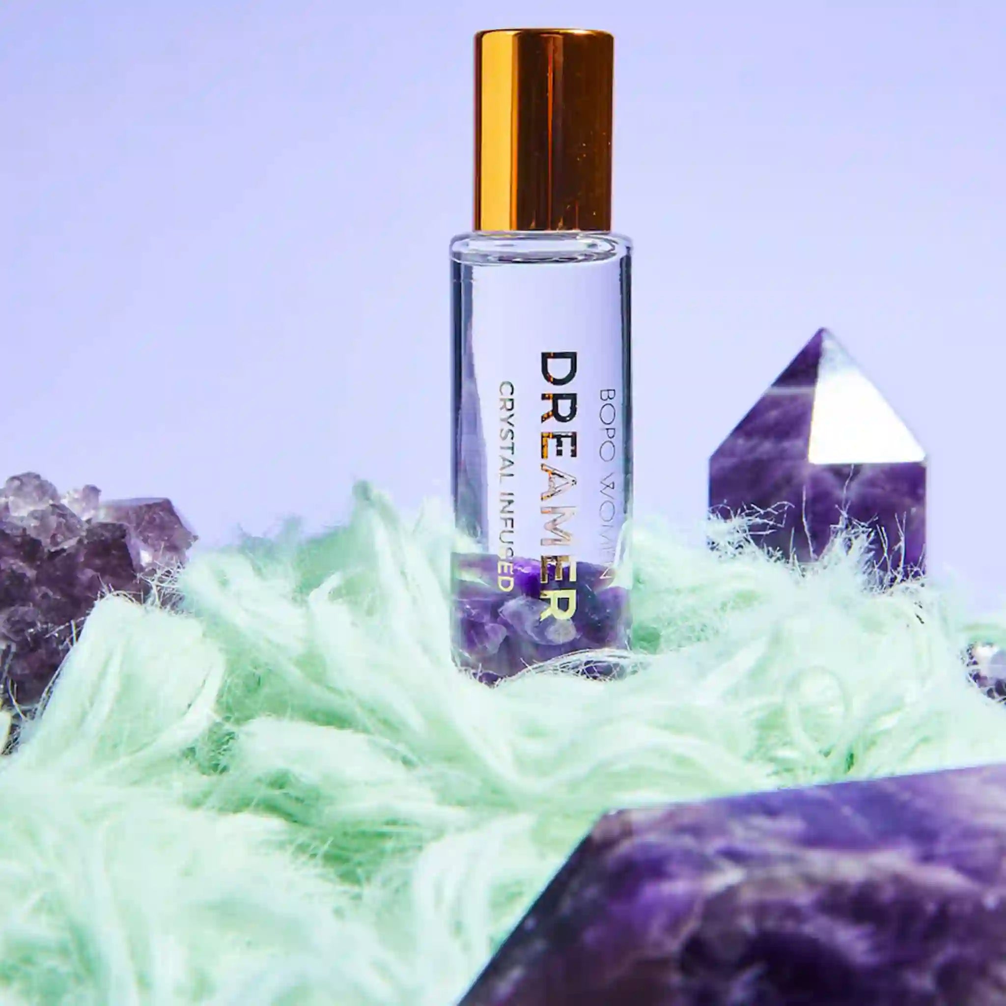 Roll-on bottle labeled 'Dreamer' with crystals and greenery in the background