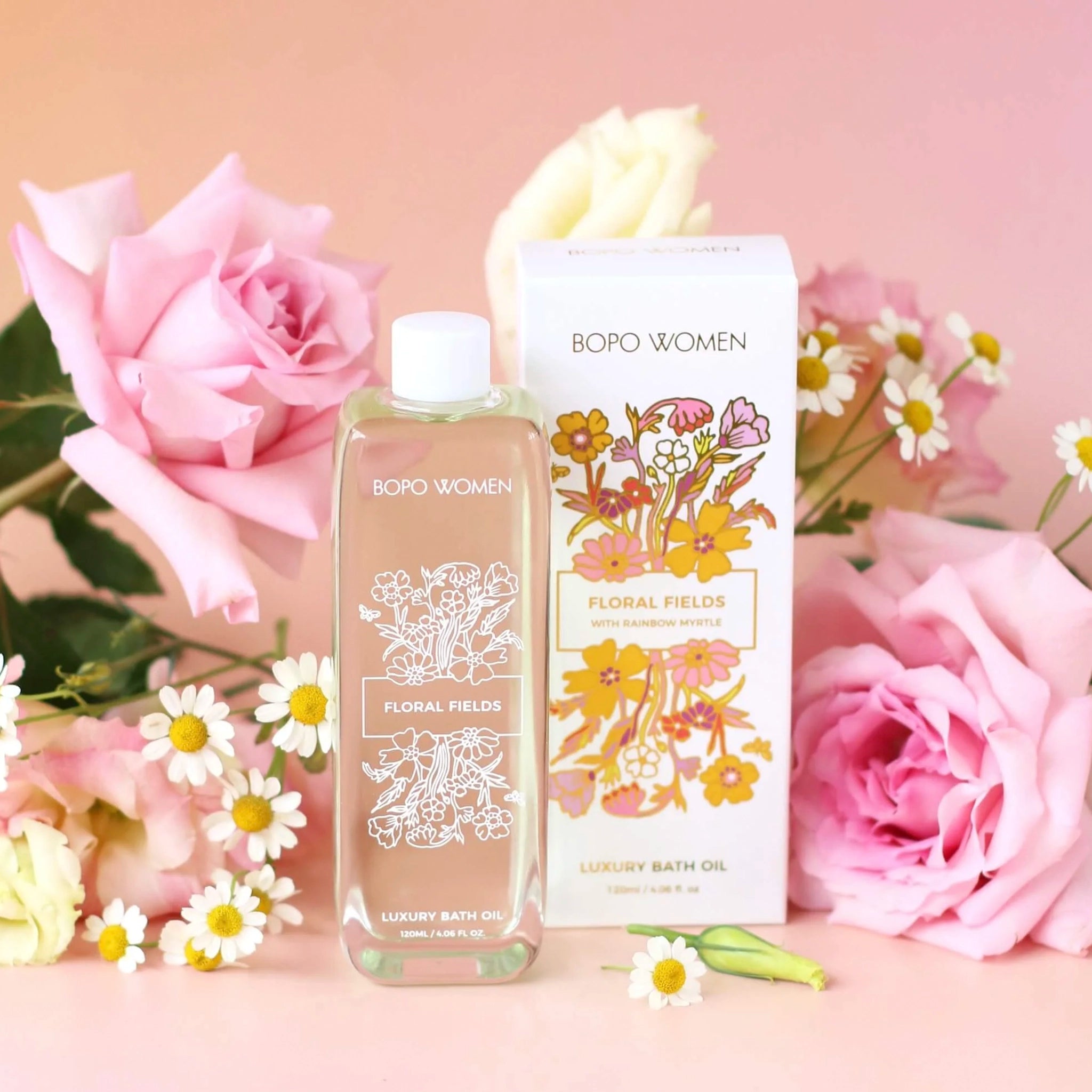 Bath oil bottle and packaging with floral design on a pink background