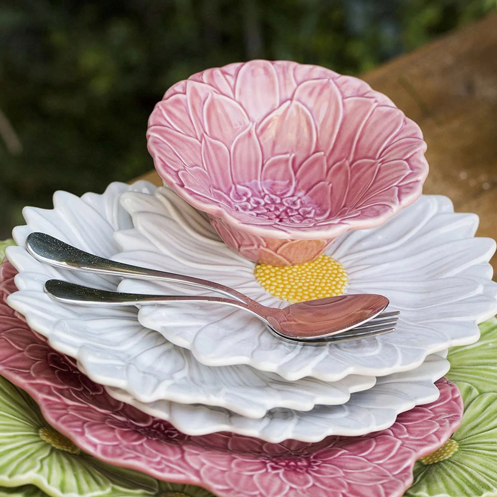 Set of ceramic plates and bowls with floral patterns on a wooden surface.