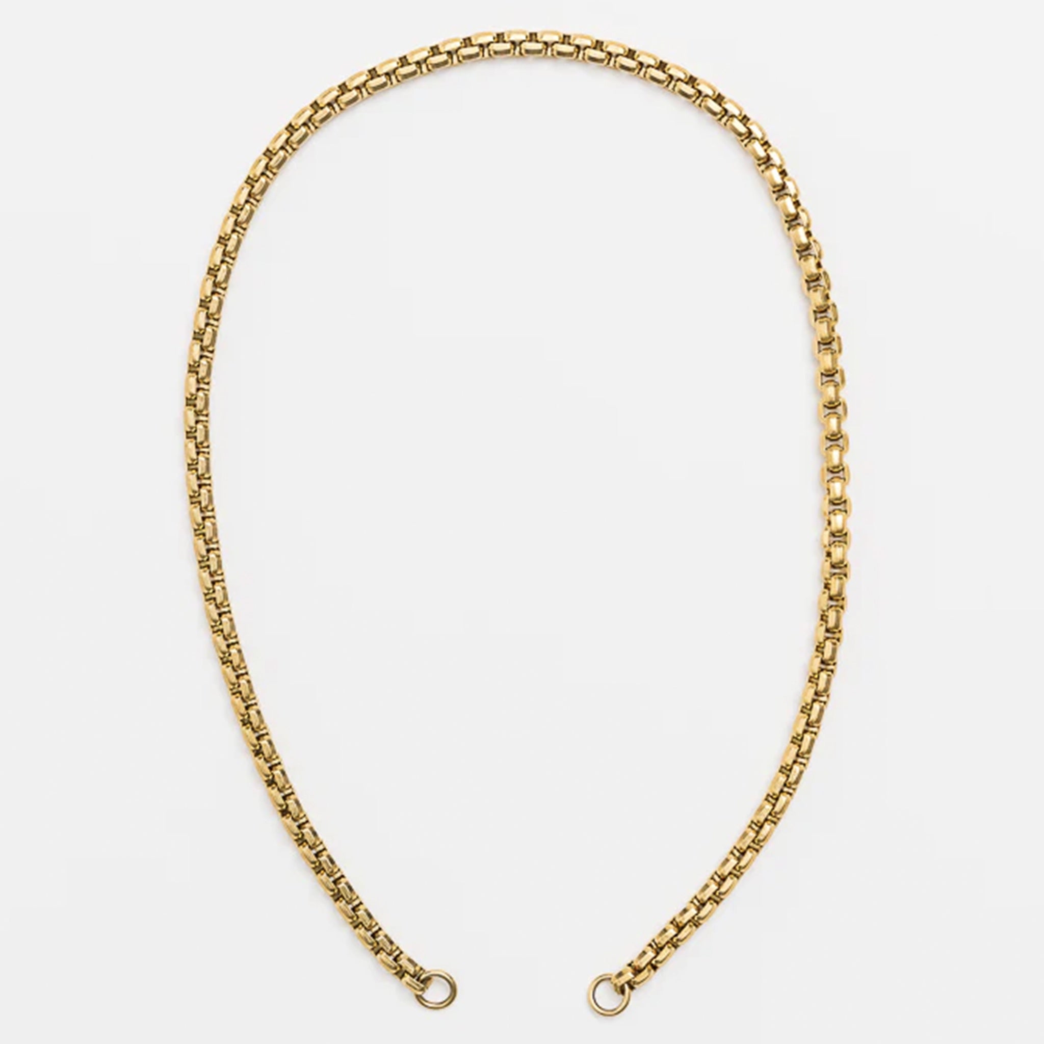 Gold chain necklace on a light gray background