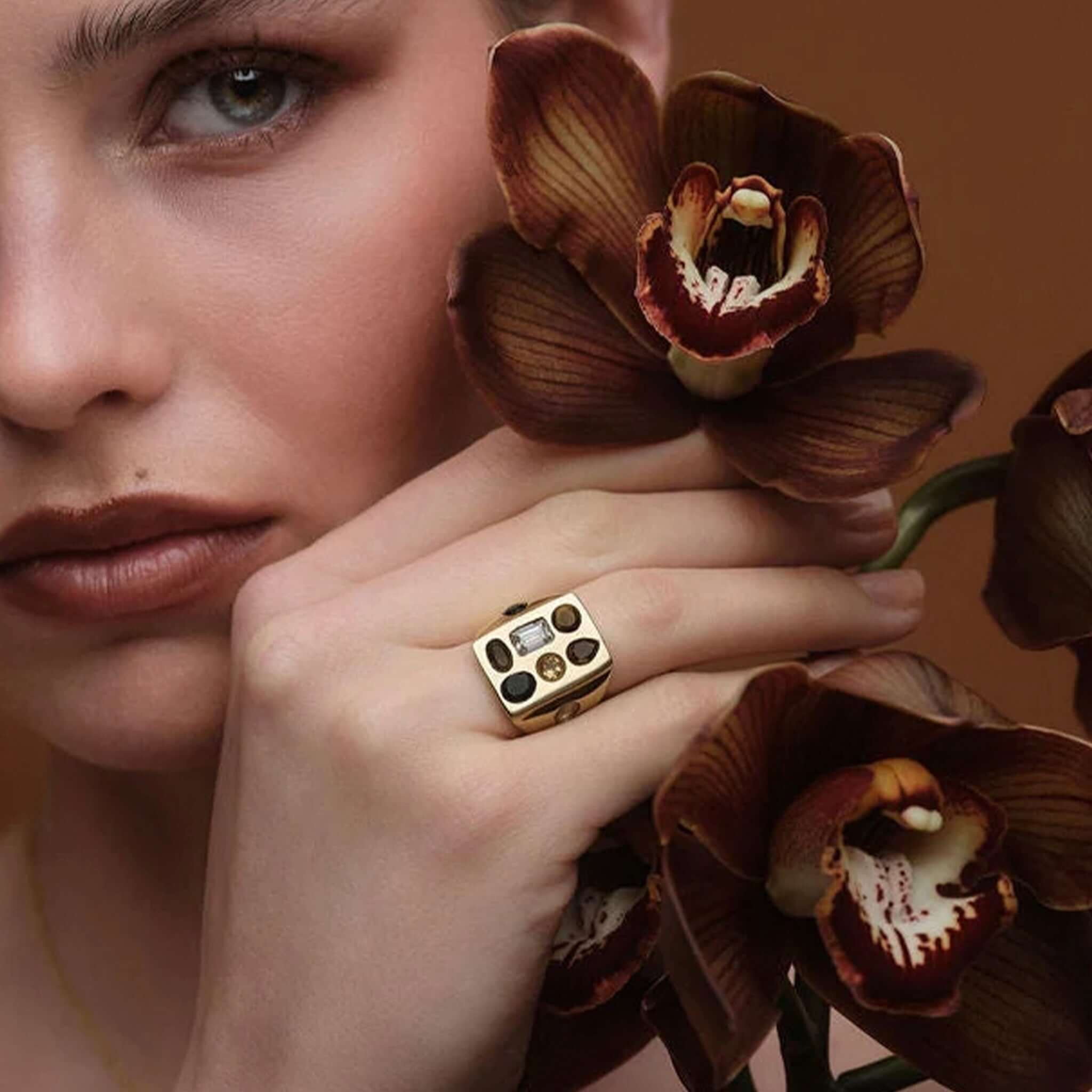 Cathy Pope Elements Collection Gold Ring - Earth elegantly showcased on model's hand with orchid flowers.