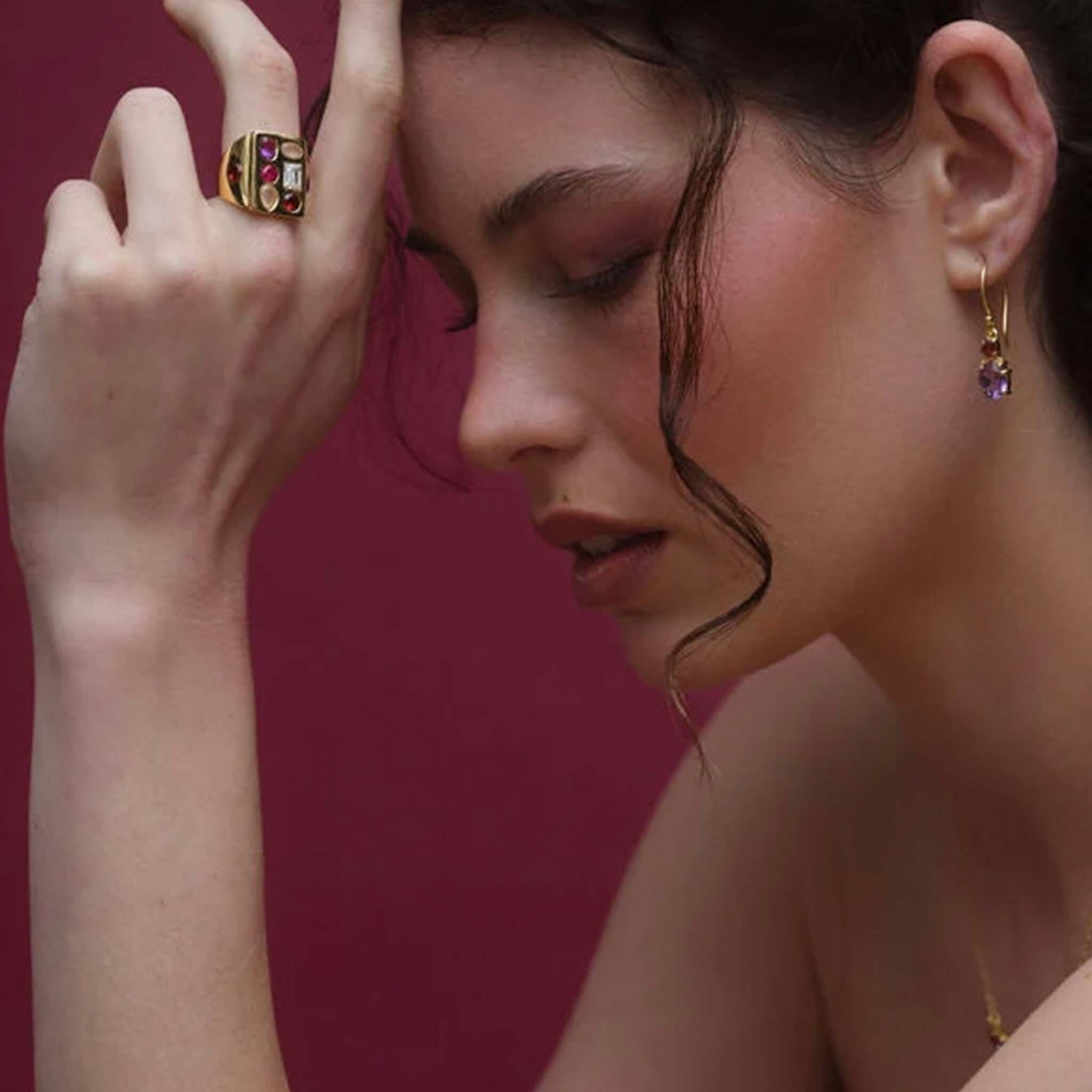 Cathy Pope Elements Collection Gold Ring - Fire showcased on a model's hand against a deep red background.