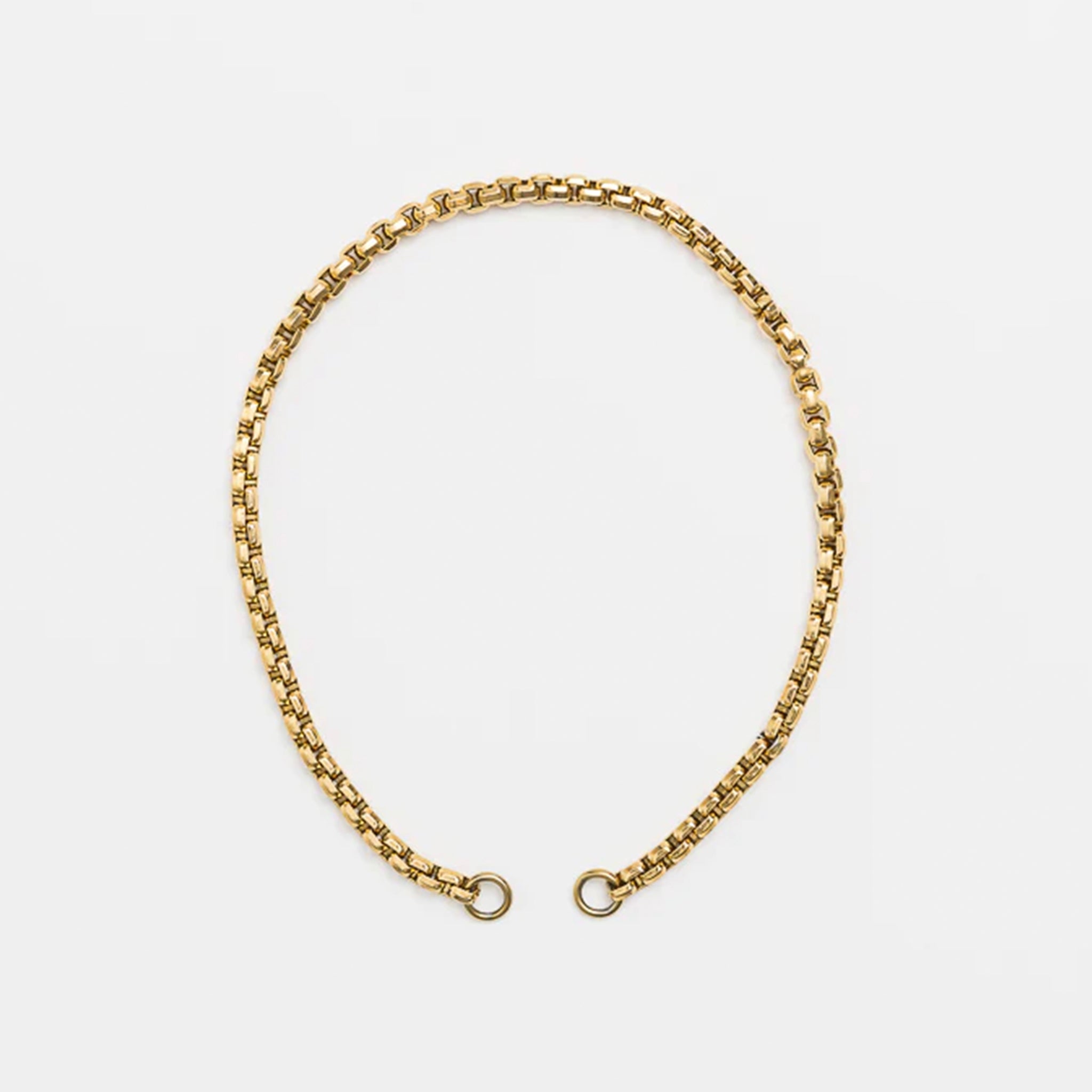 Gold chain necklace on a light gray background