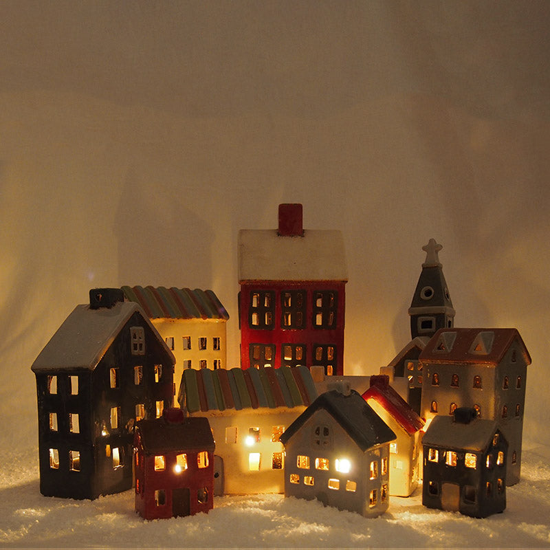 Model houses with lights on a snowy surface against a dark background