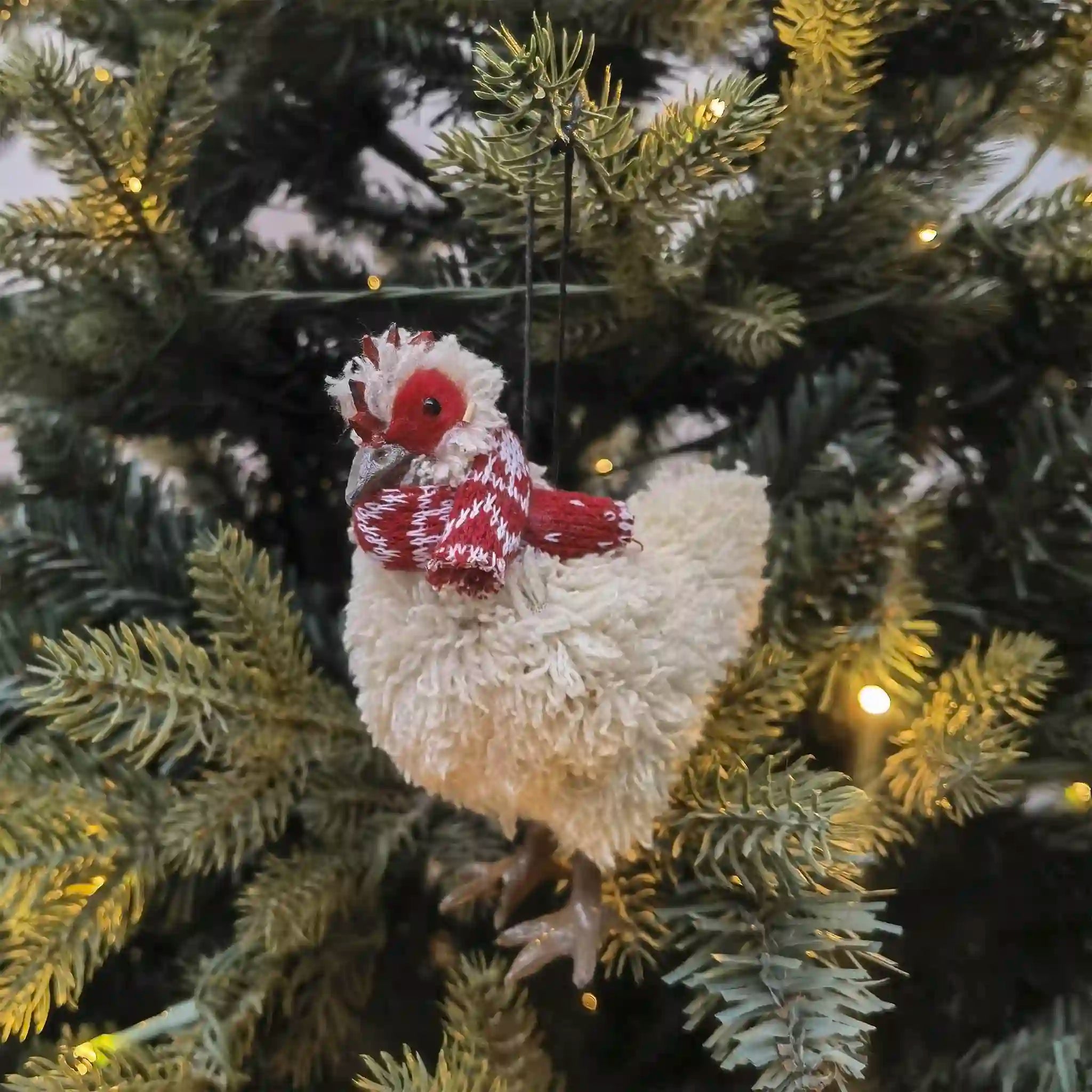 Decorative chicken ornament hanging on a Christmas tree.