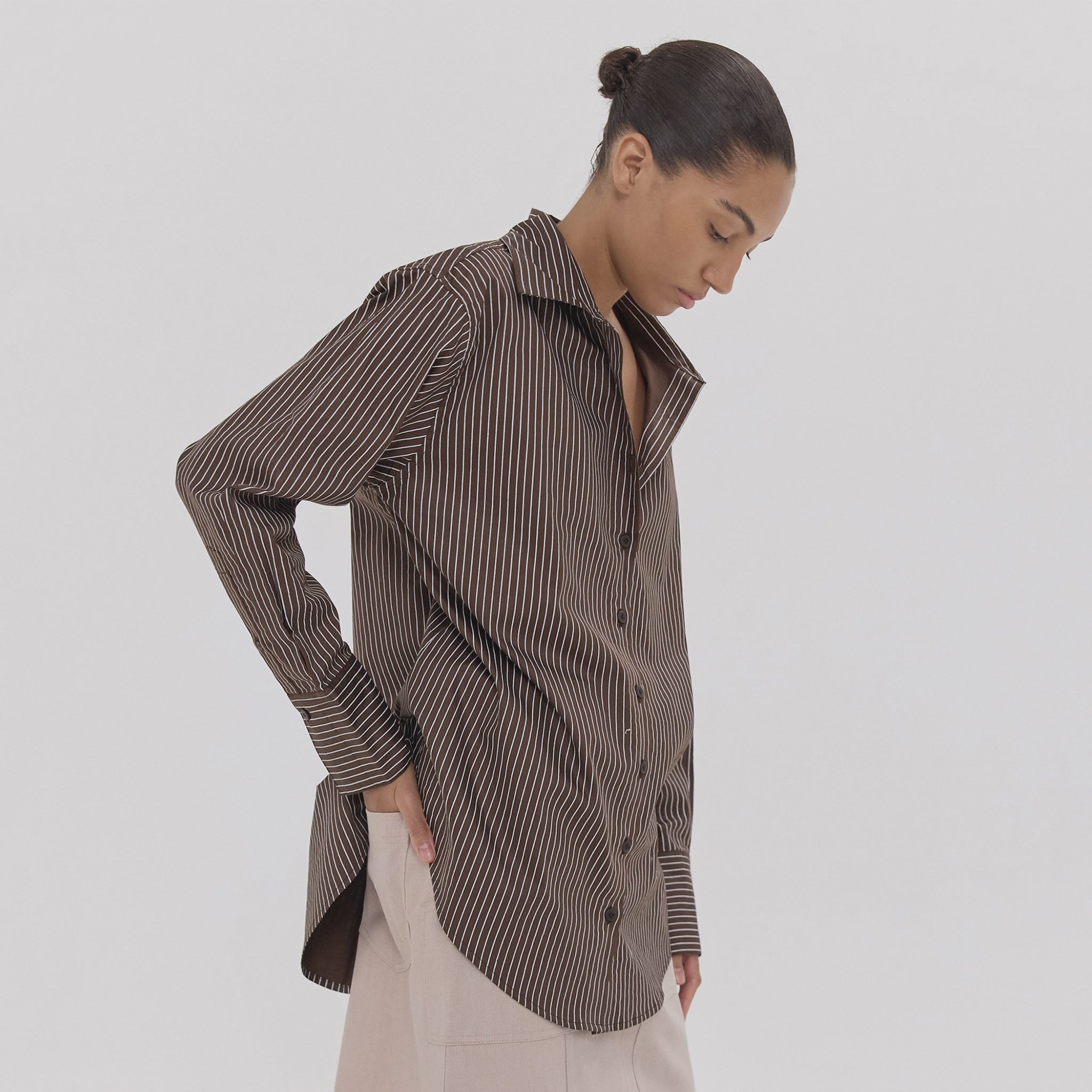 Woman wearing a brown striped shirt on a white background