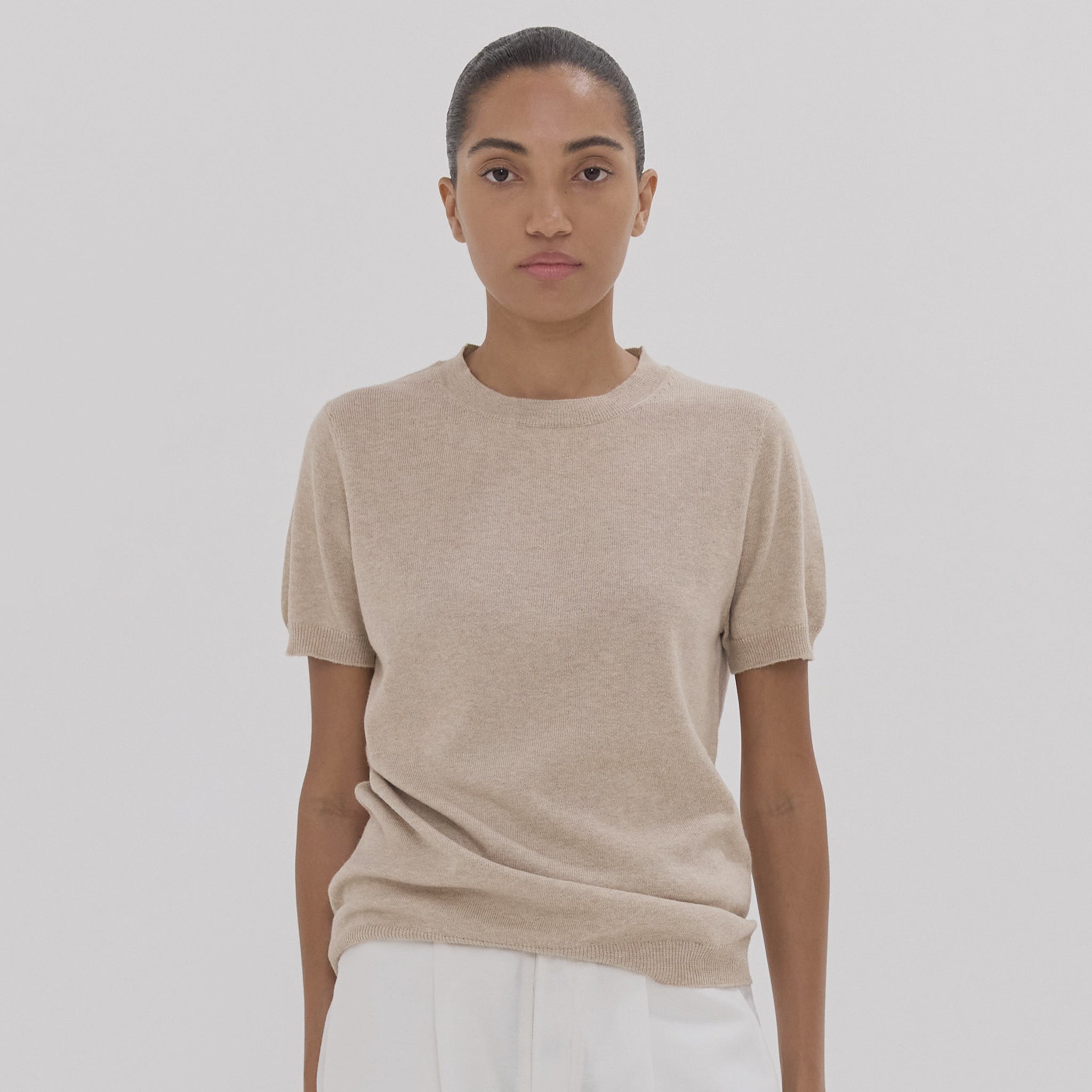 Person wearing a beige t-shirt against a plain background