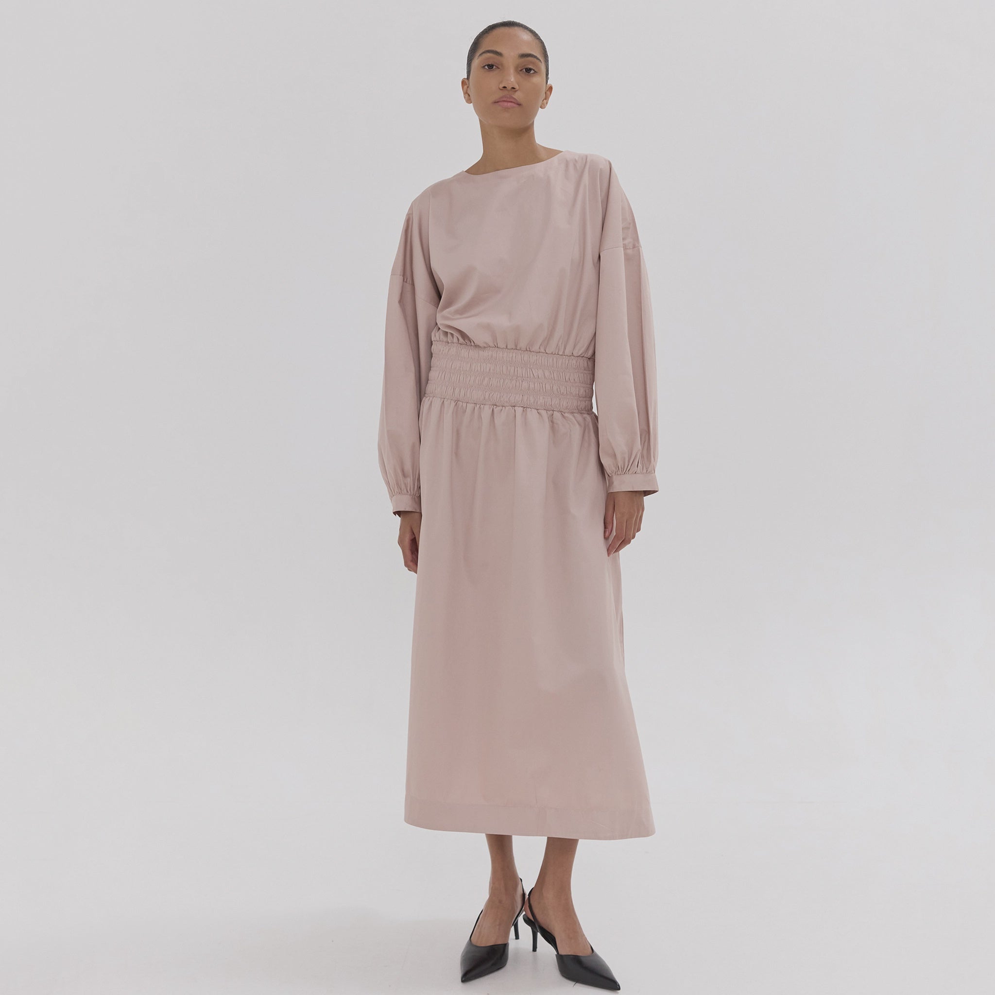 Woman wearing a light pink dress on a white background