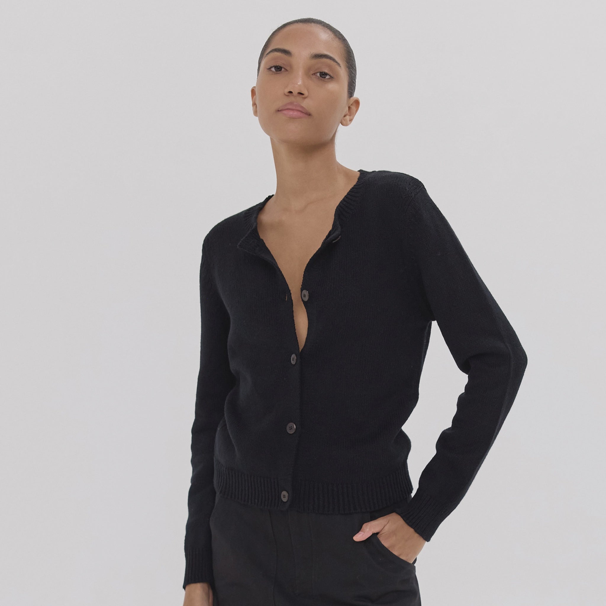 Person wearing a black cardigan against a plain background