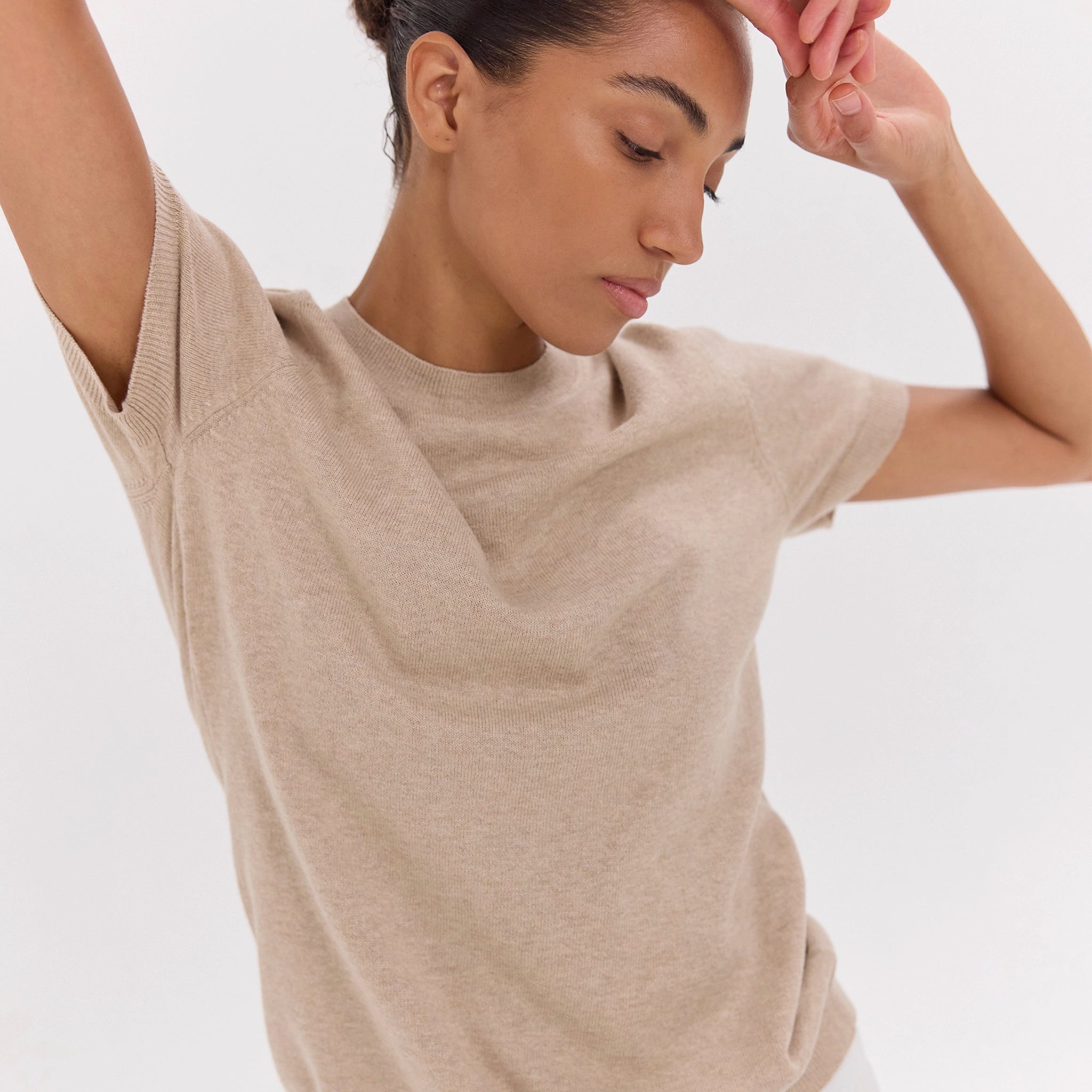 Woman wearing a beige t-shirt against a plain background