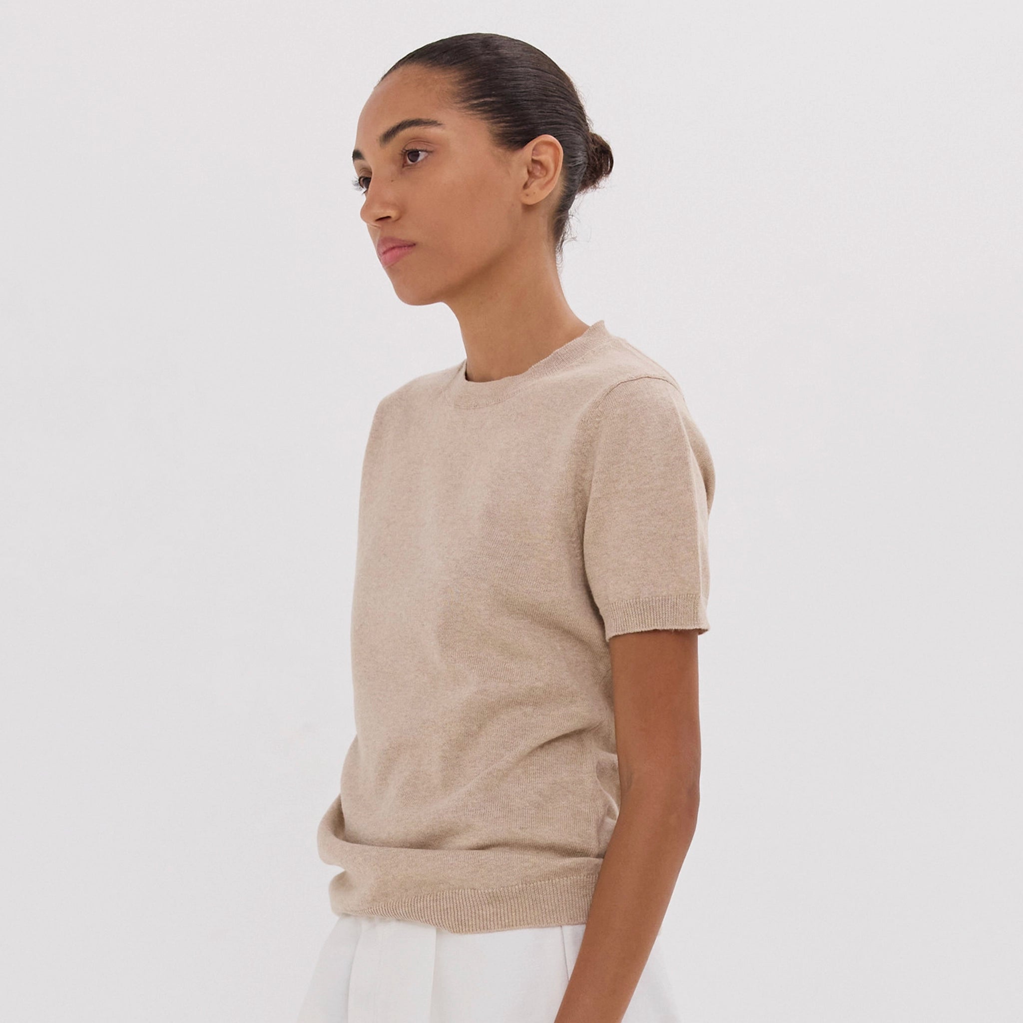 Woman wearing a beige sweater against a white background